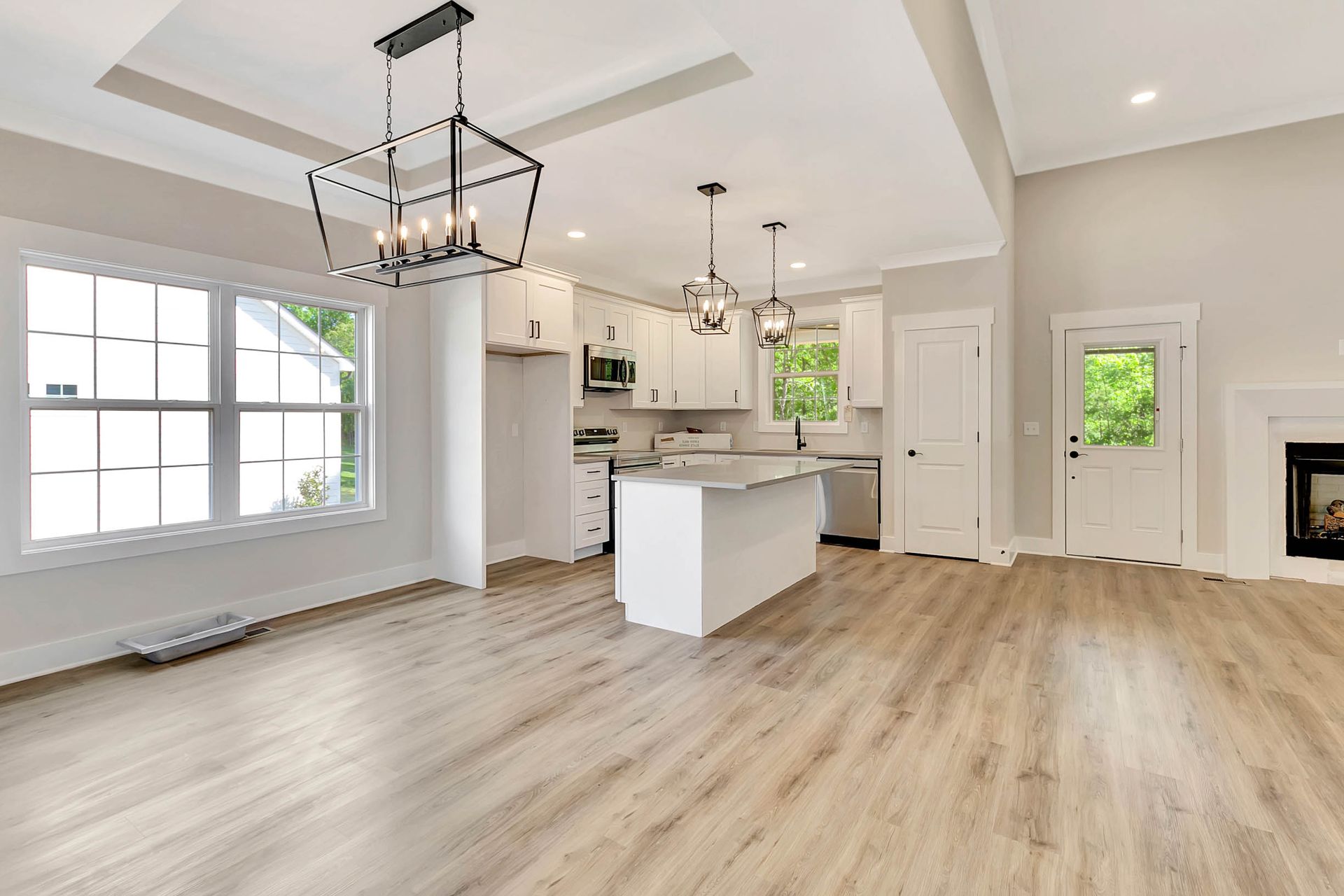A living room with hardwood floors , a kitchen , and a fireplace.