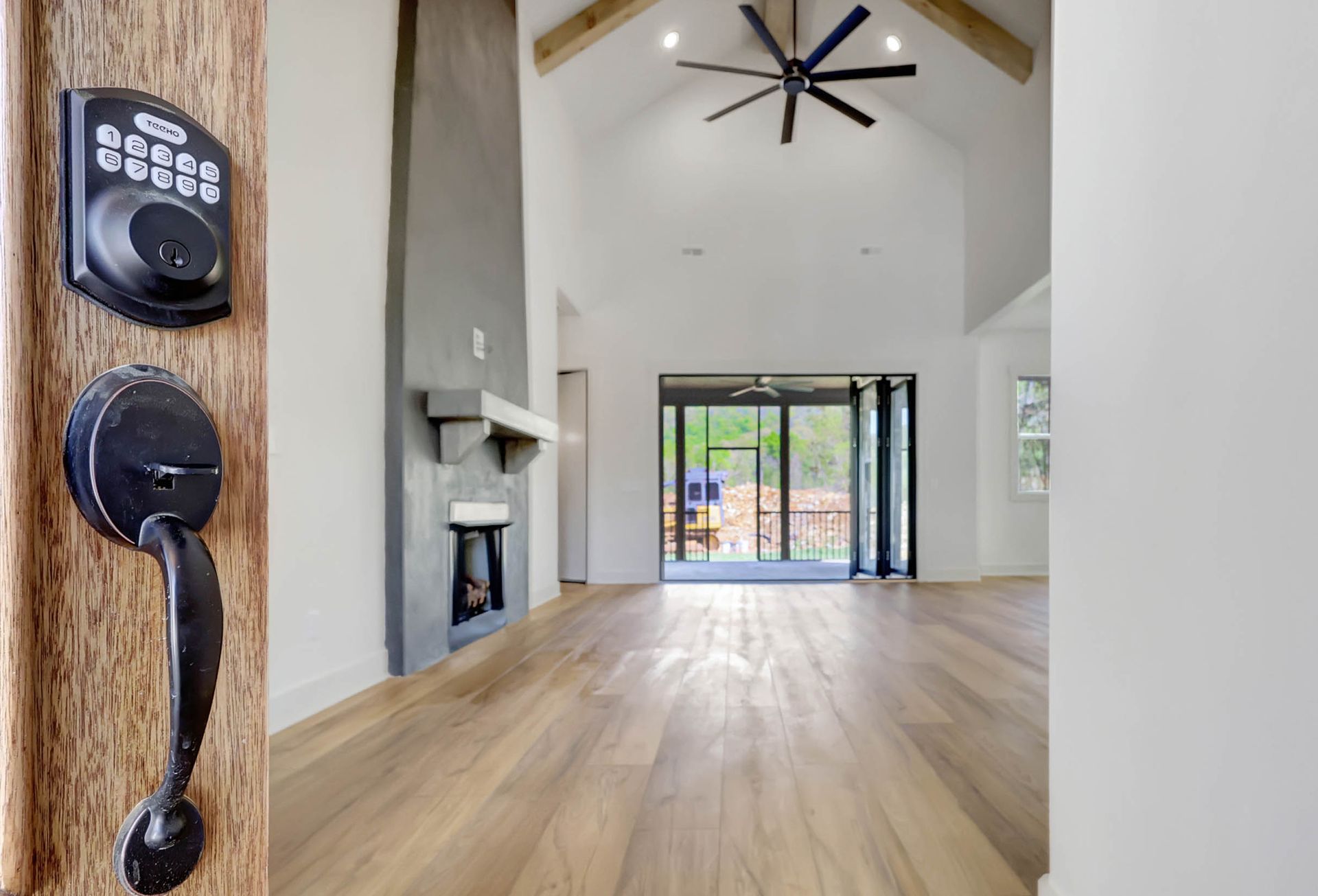 A door with a lock on it is open to a living room with hardwood floors and a ceiling fan.