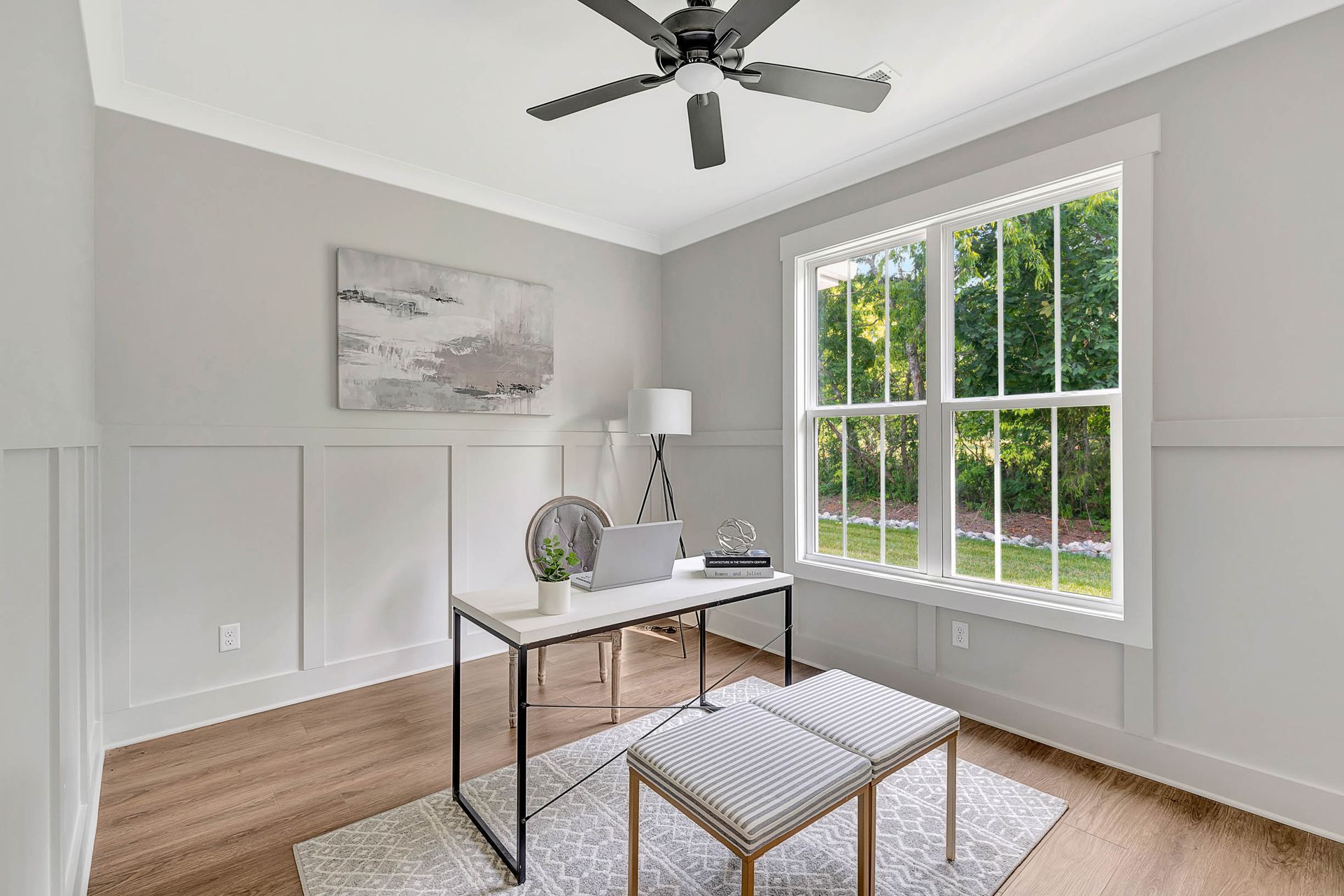 A home office with a desk and a ceiling fan.