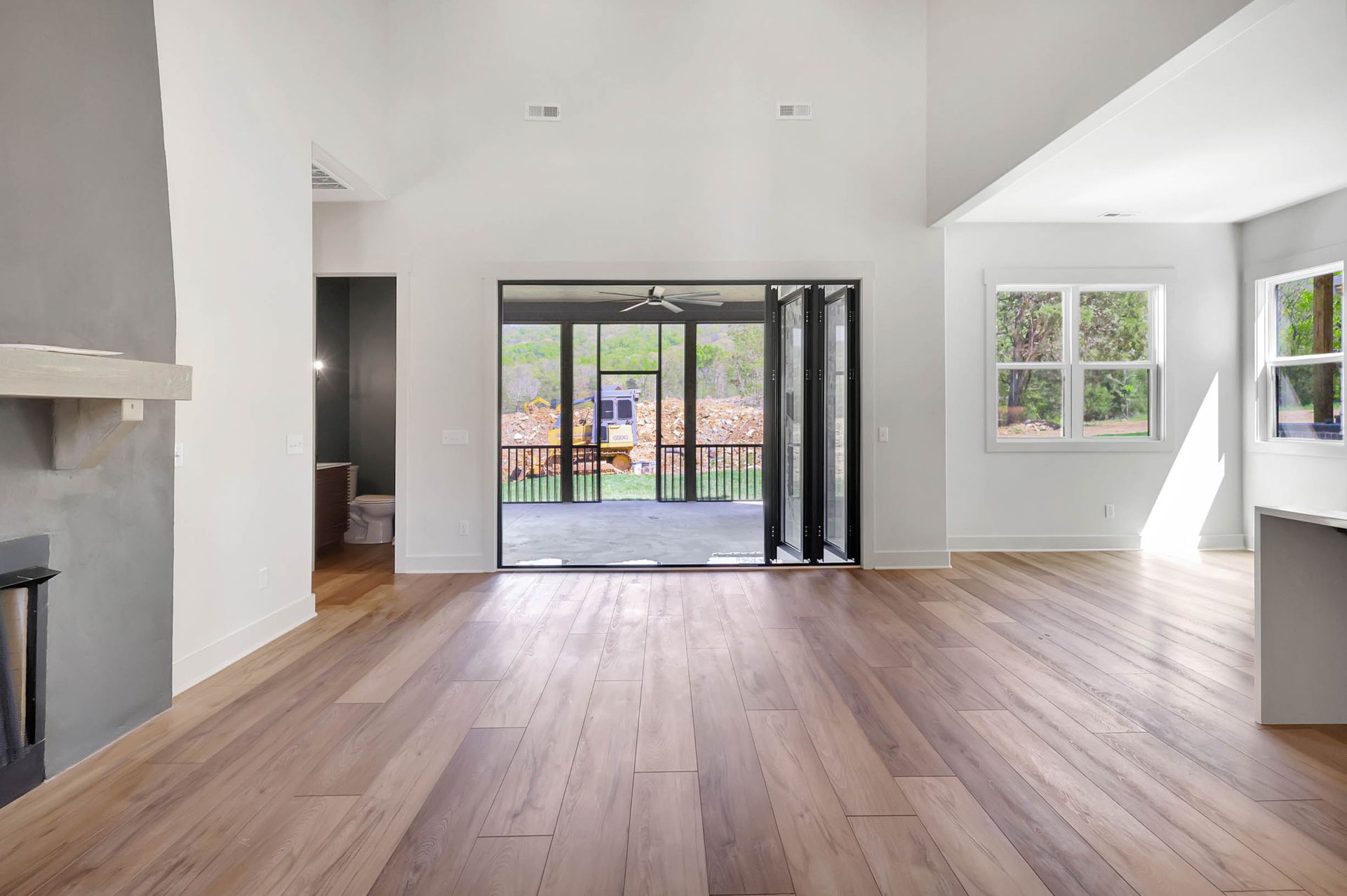 An empty living room with hardwood floors and sliding glass doors leading to a patio.
