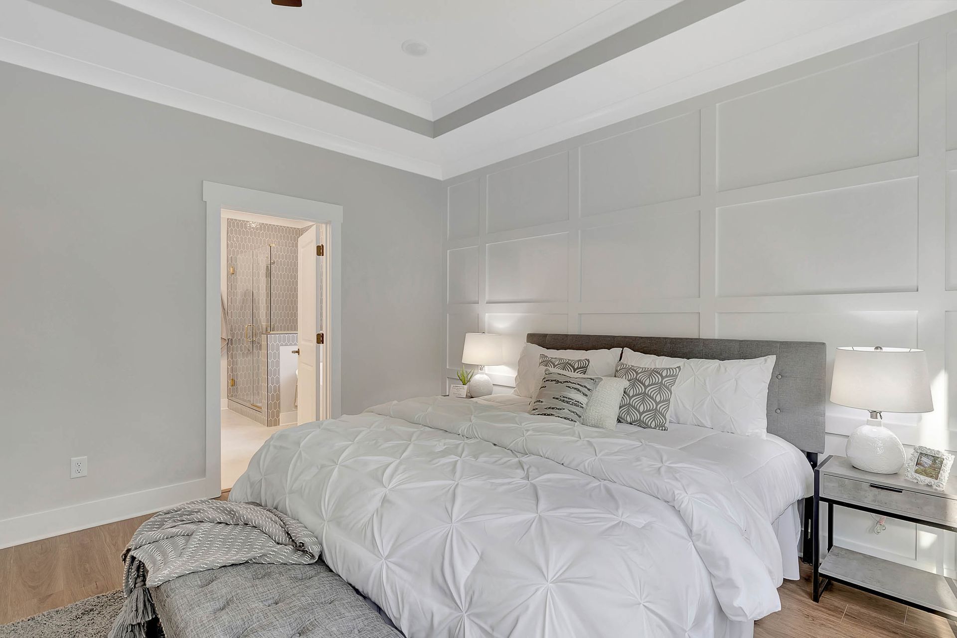 A bedroom with a large bed , nightstands , lamps and a ceiling fan.