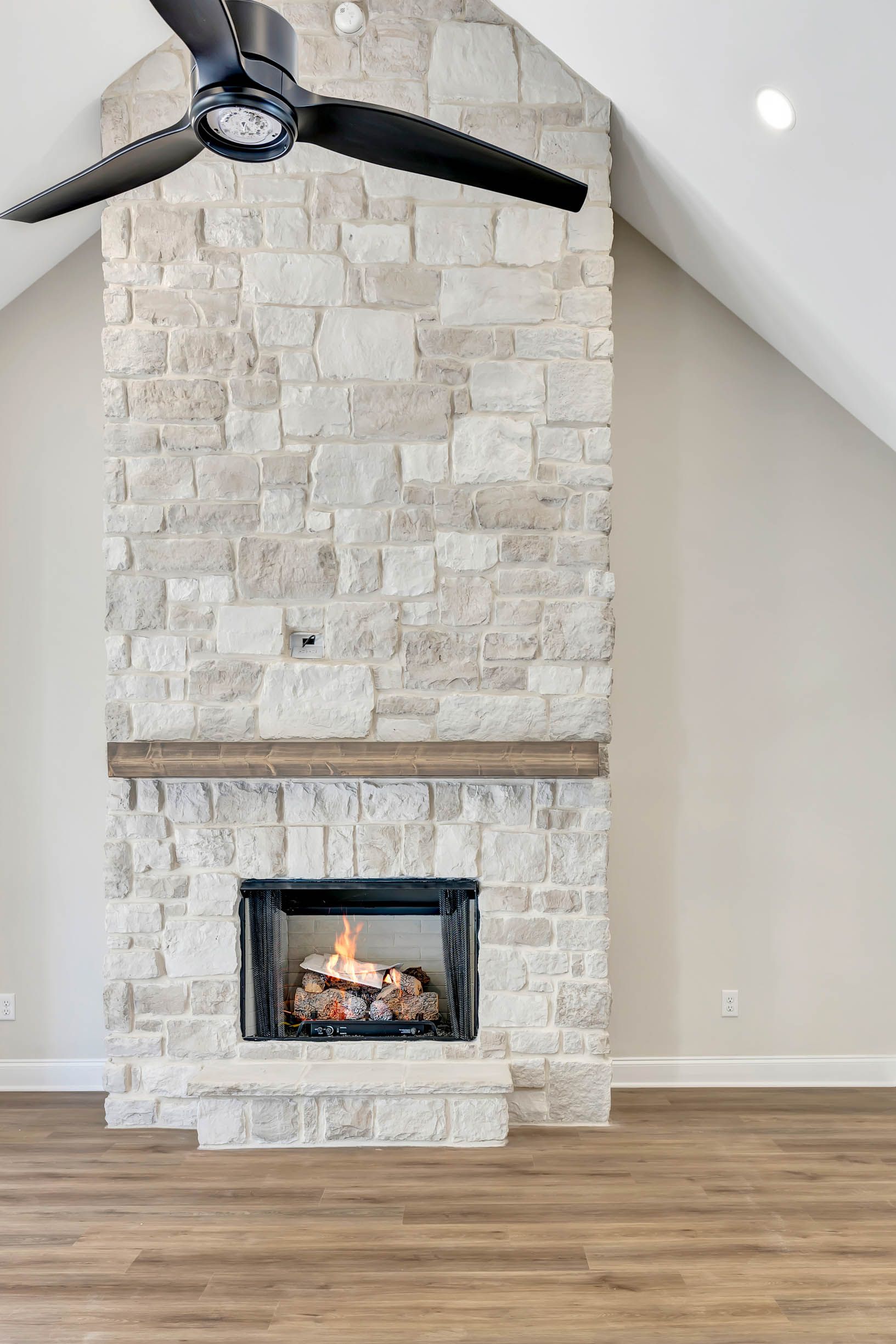 A living room with a fireplace and a ceiling fan.