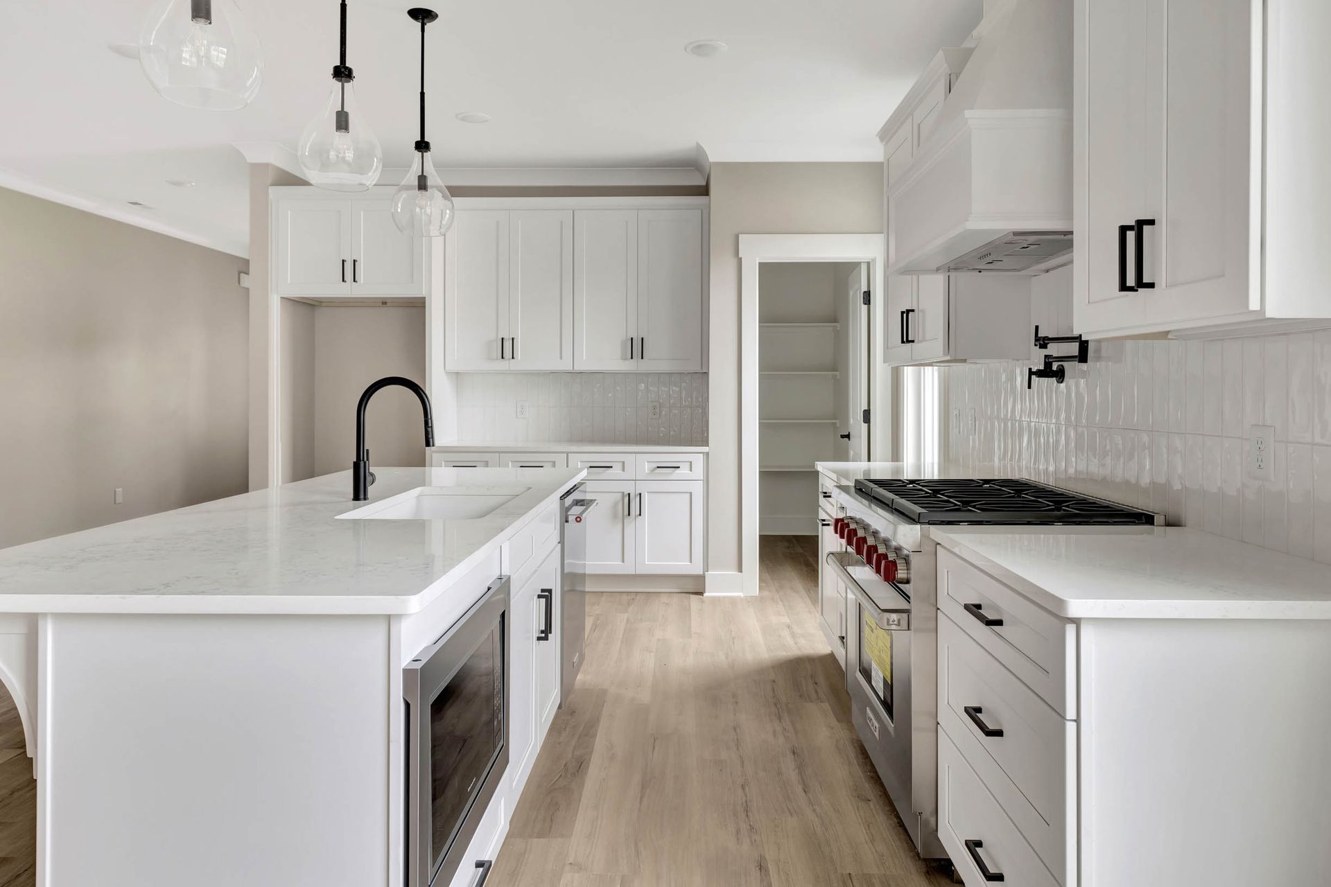A kitchen with white cabinets , stainless steel appliances , and a large island.