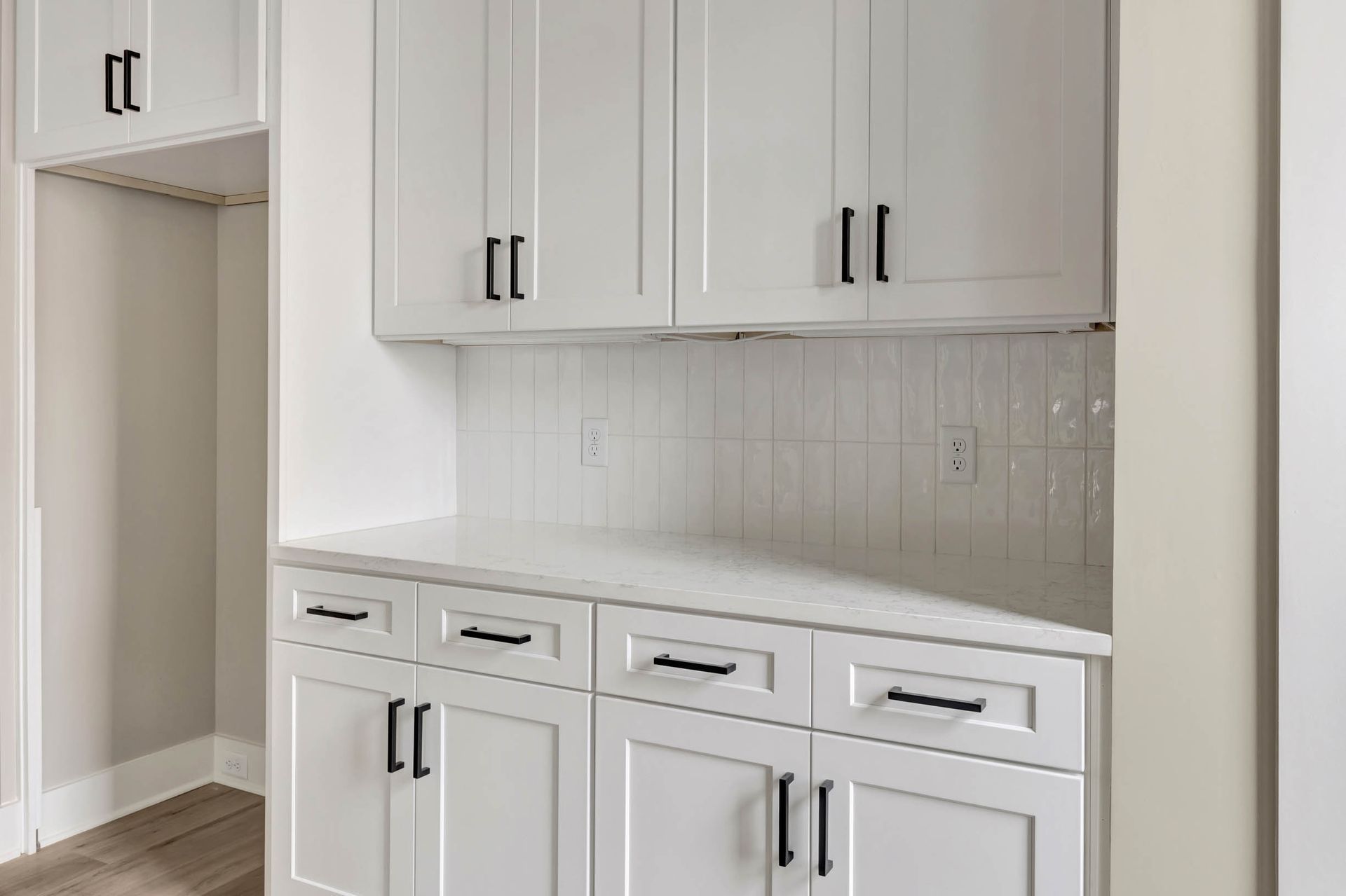 A kitchen with white cabinets and white counter tops.