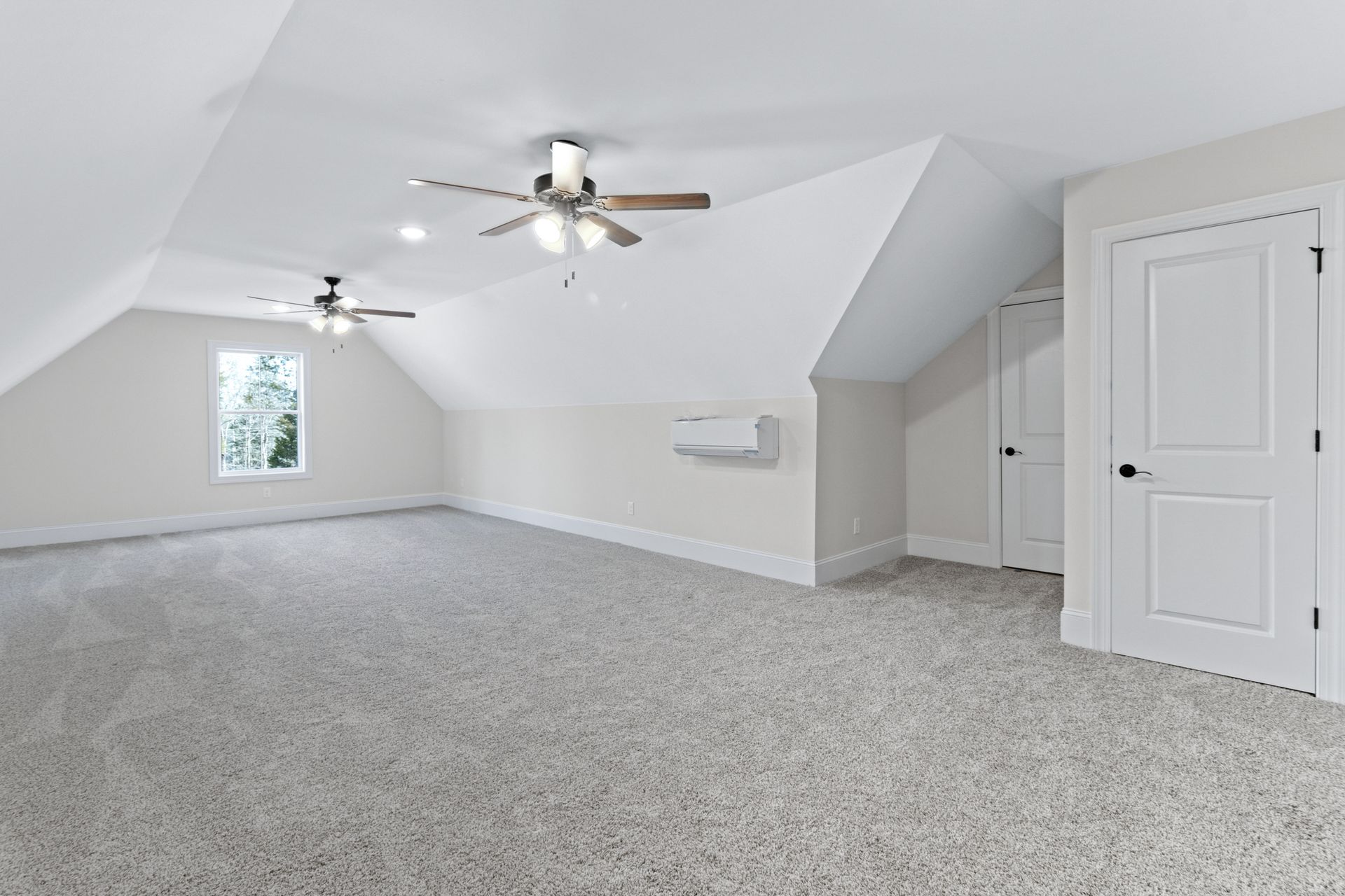 An empty room with a ceiling fan and a window.