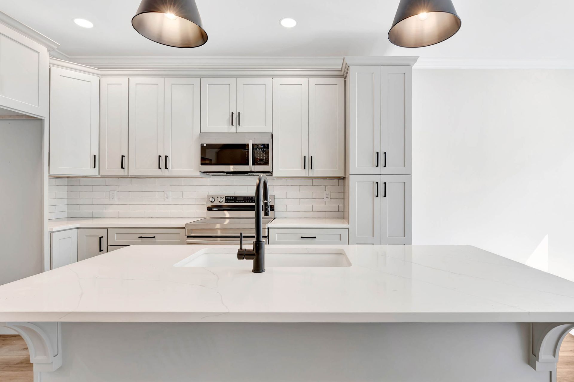 A kitchen with white cabinets , stainless steel appliances , a sink , and a large island.