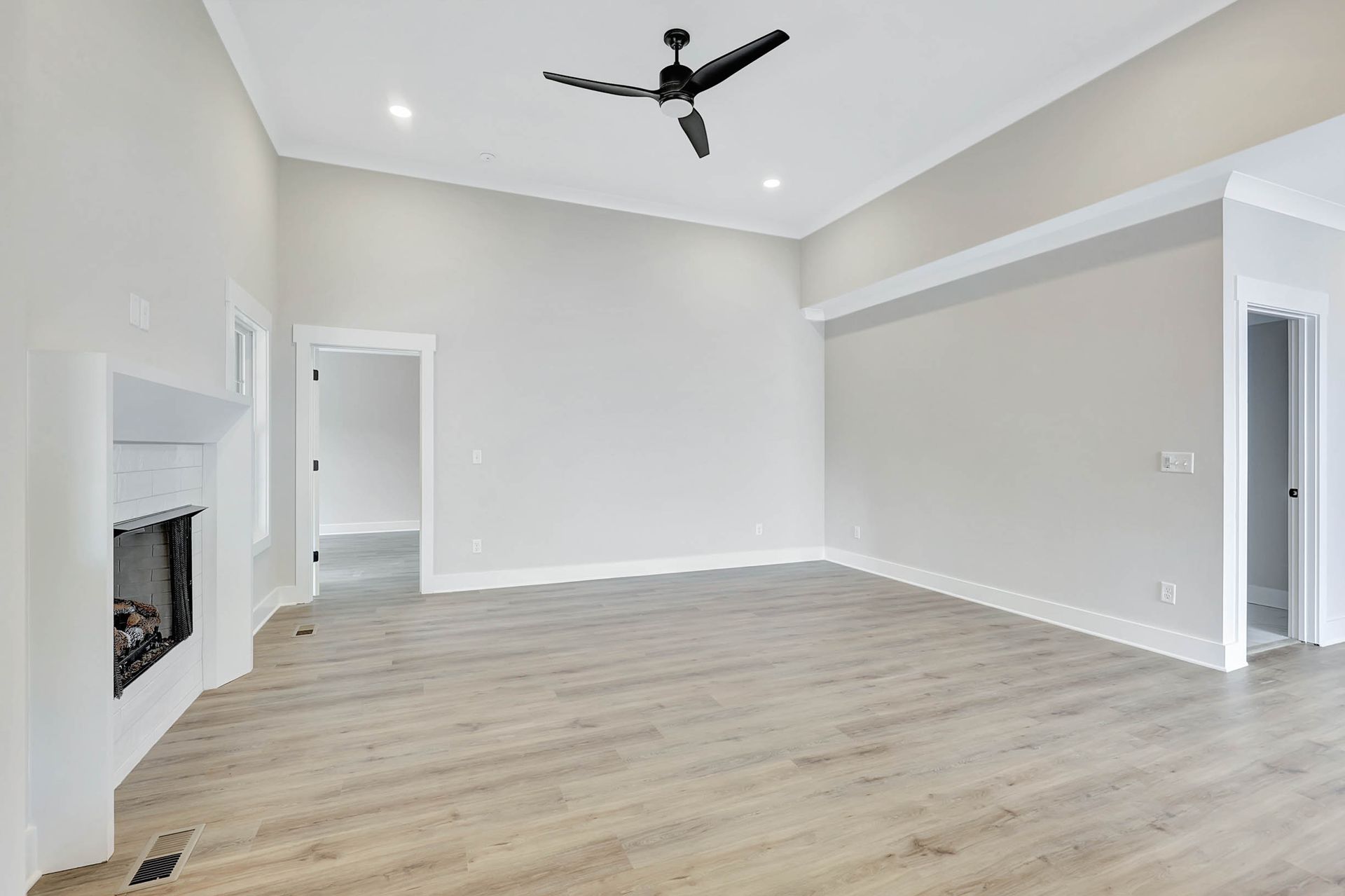 An empty living room with a fireplace and ceiling fan.