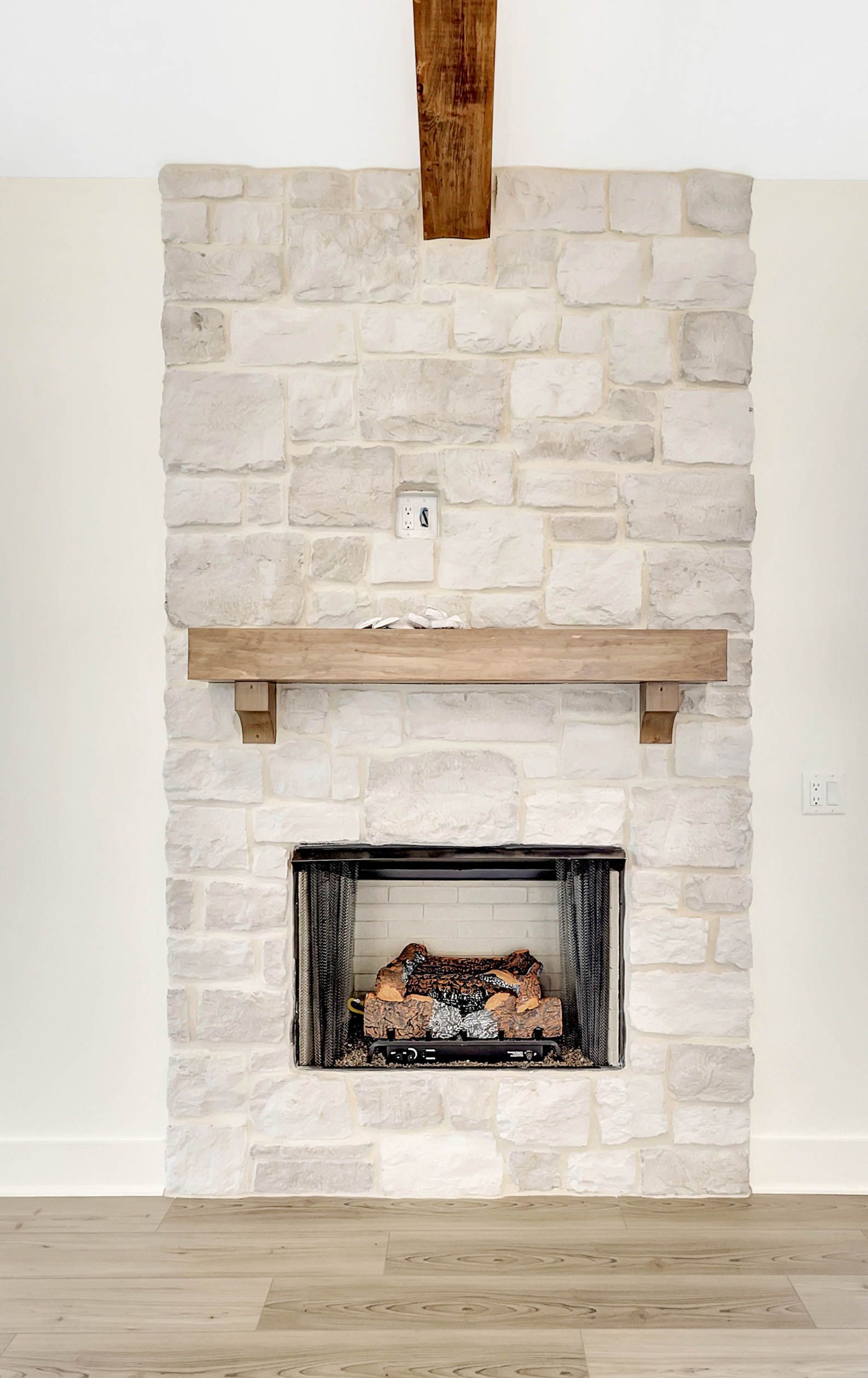 A white brick fireplace with a wooden mantle in a living room.