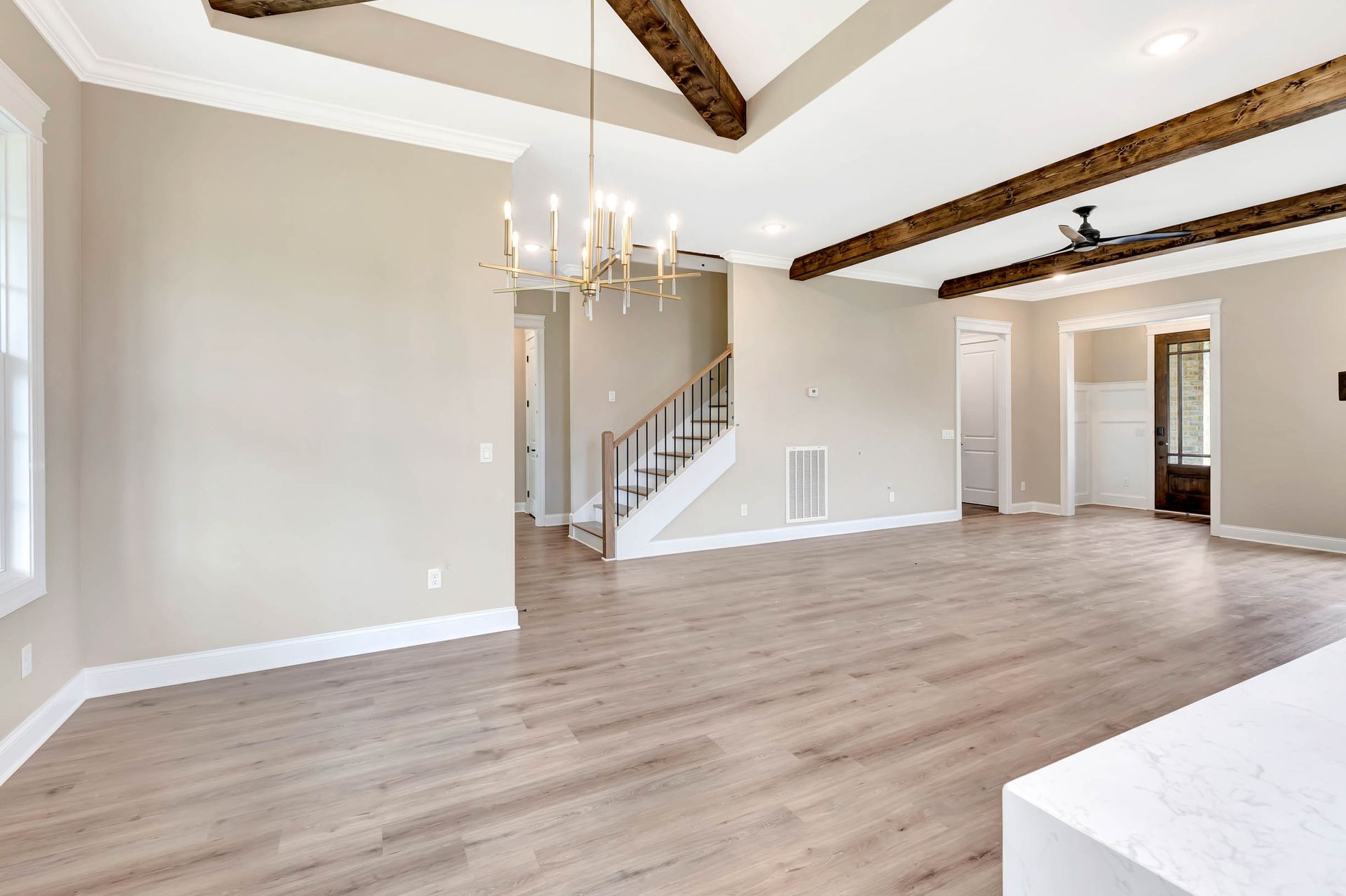 An empty living room with hardwood floors and a staircase.