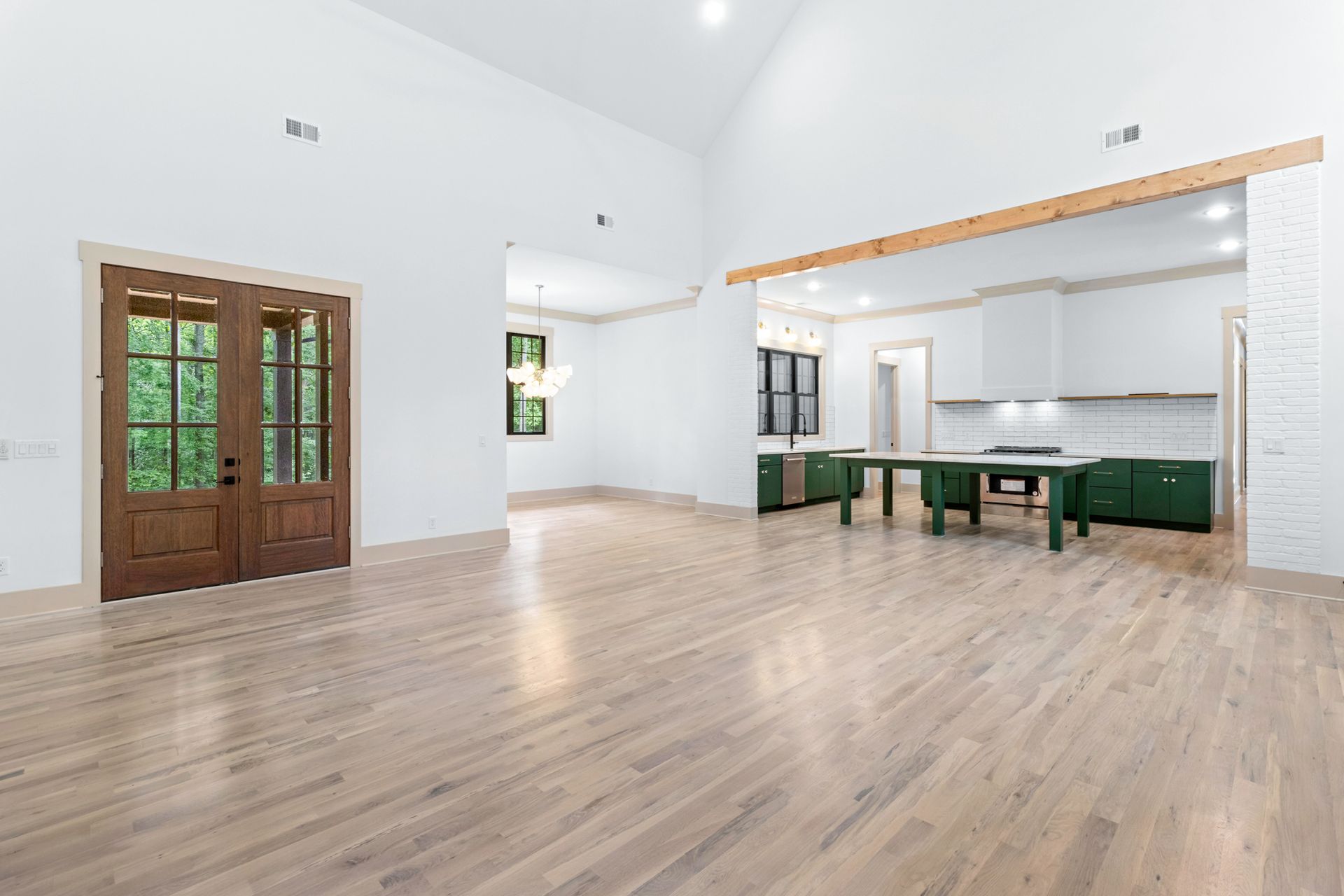 a large empty room with hardwood floors and a kitchen .