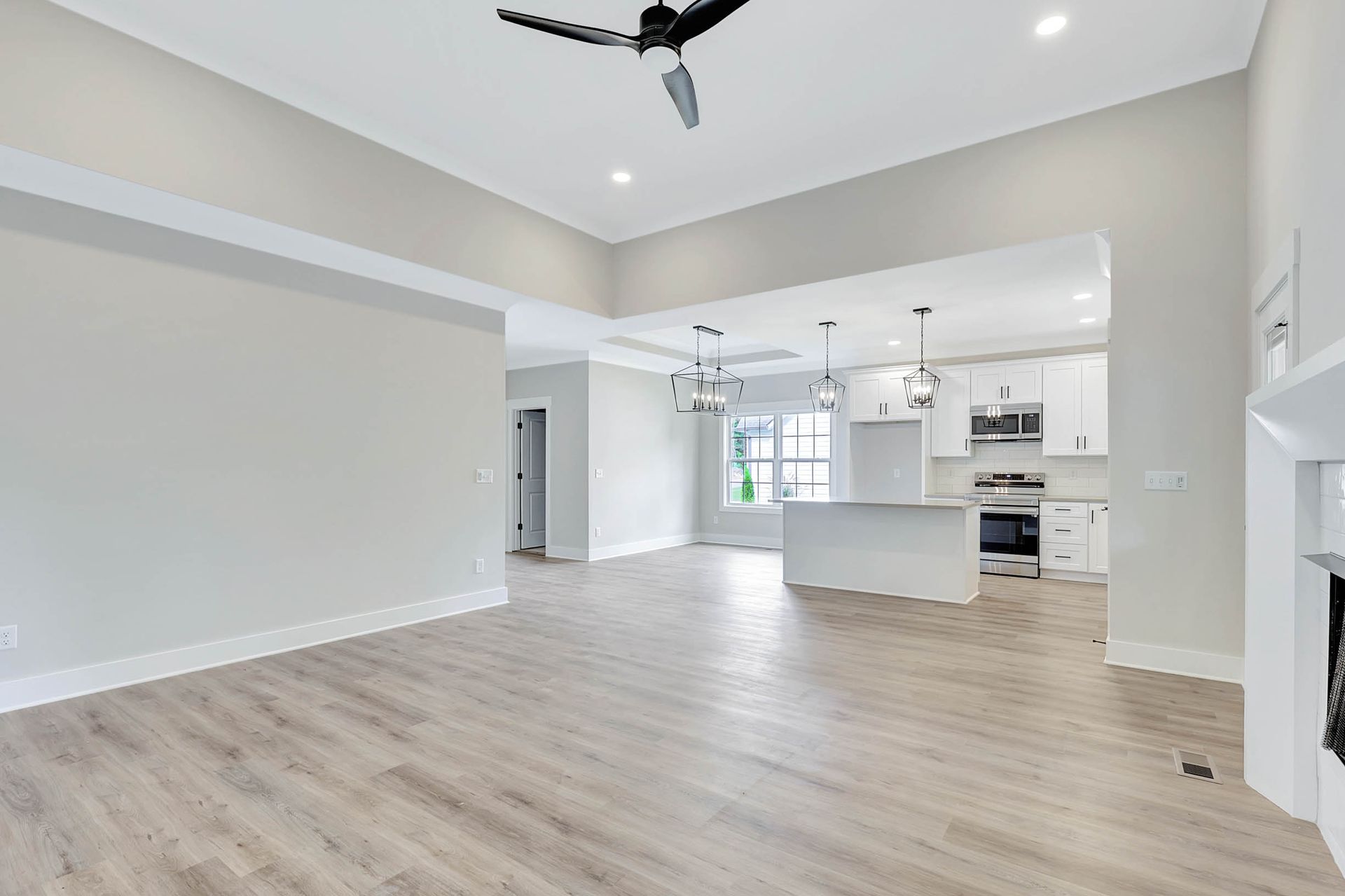 An empty living room with hardwood floors and a ceiling fan.