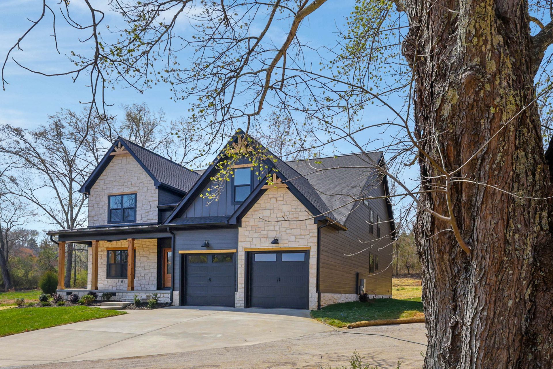 A large house with two garages and a tree in front of it.