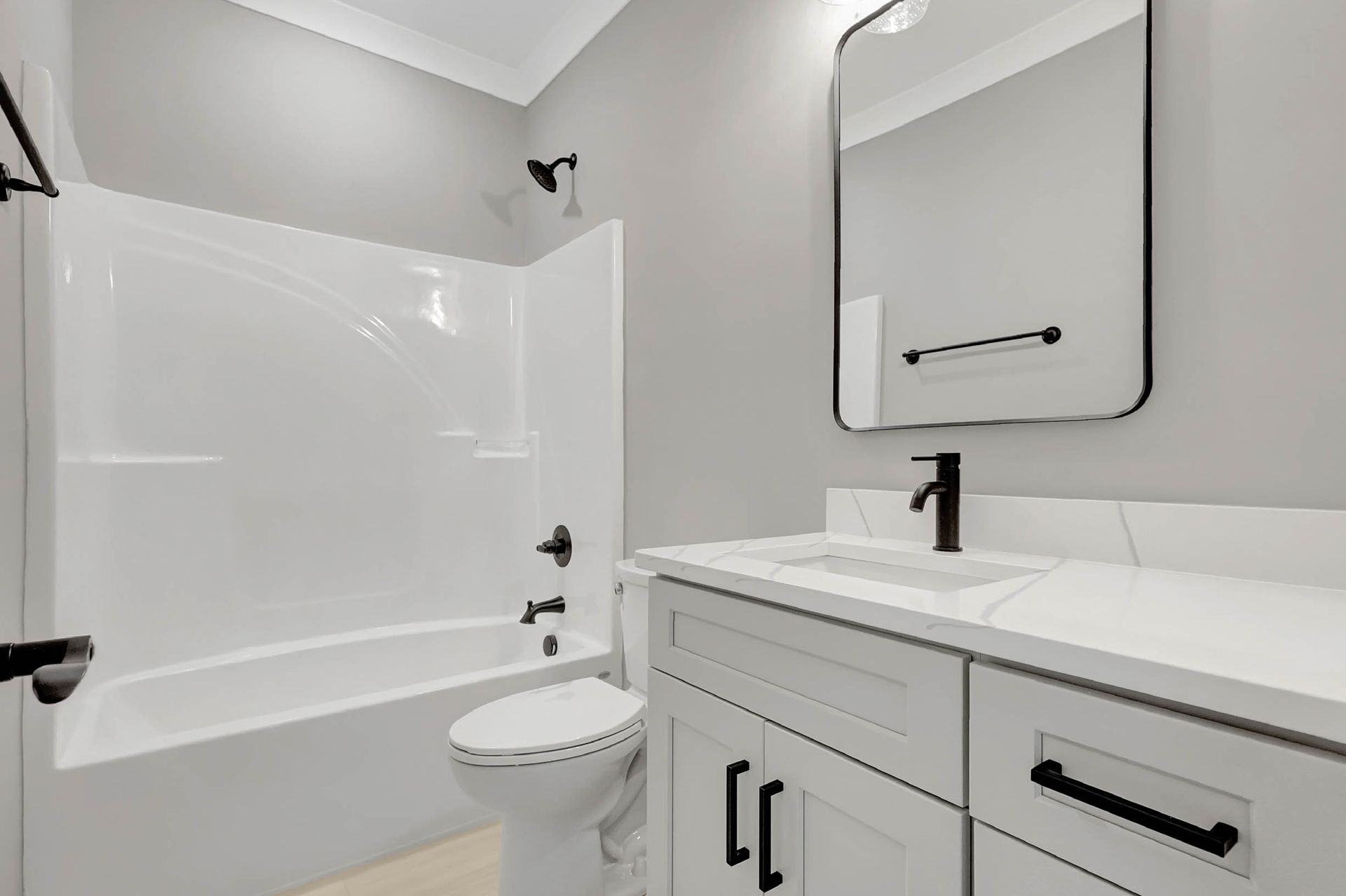 A bathroom with a toilet , sink , bathtub and mirror.