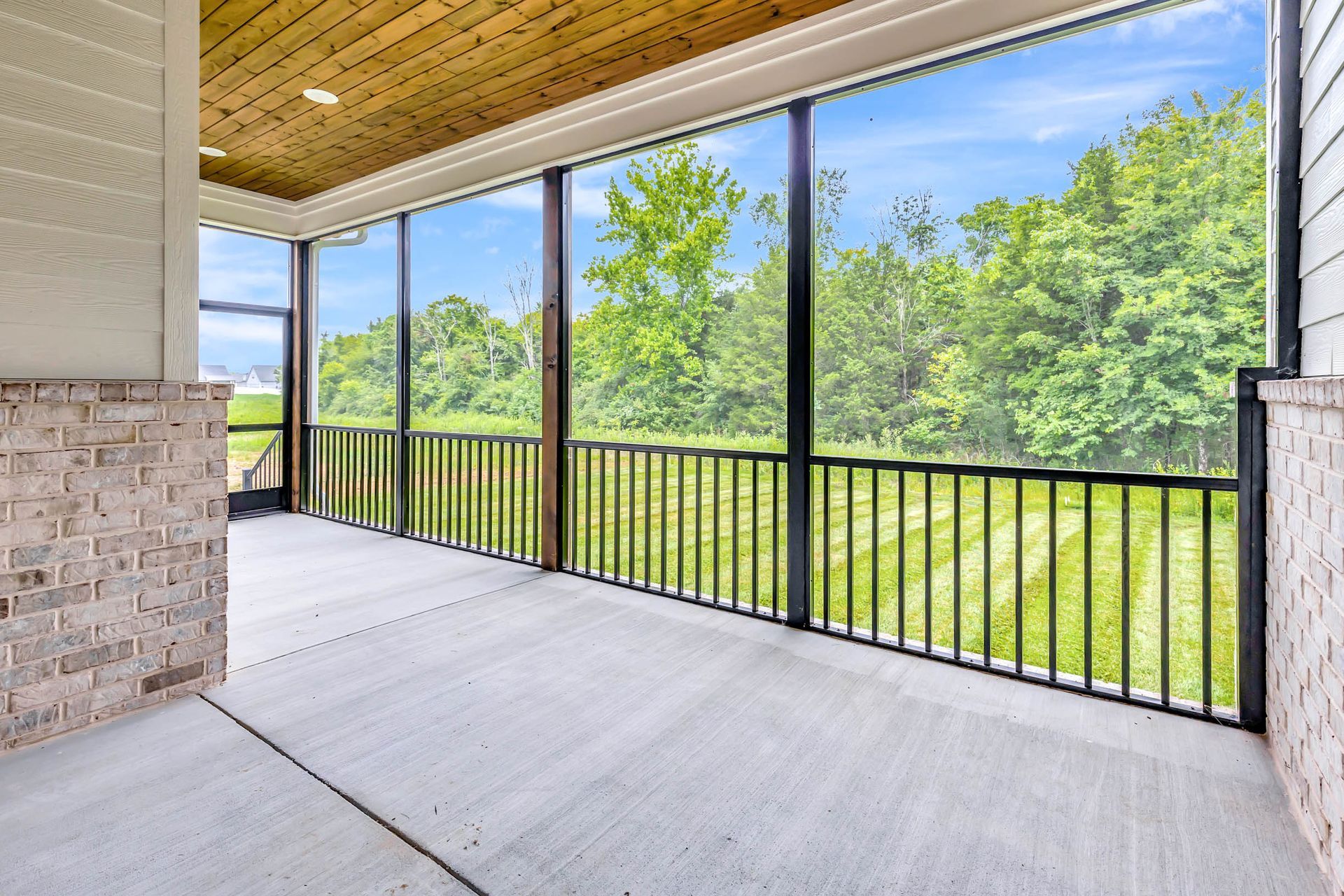 A screened in porch with a view of a field and trees.