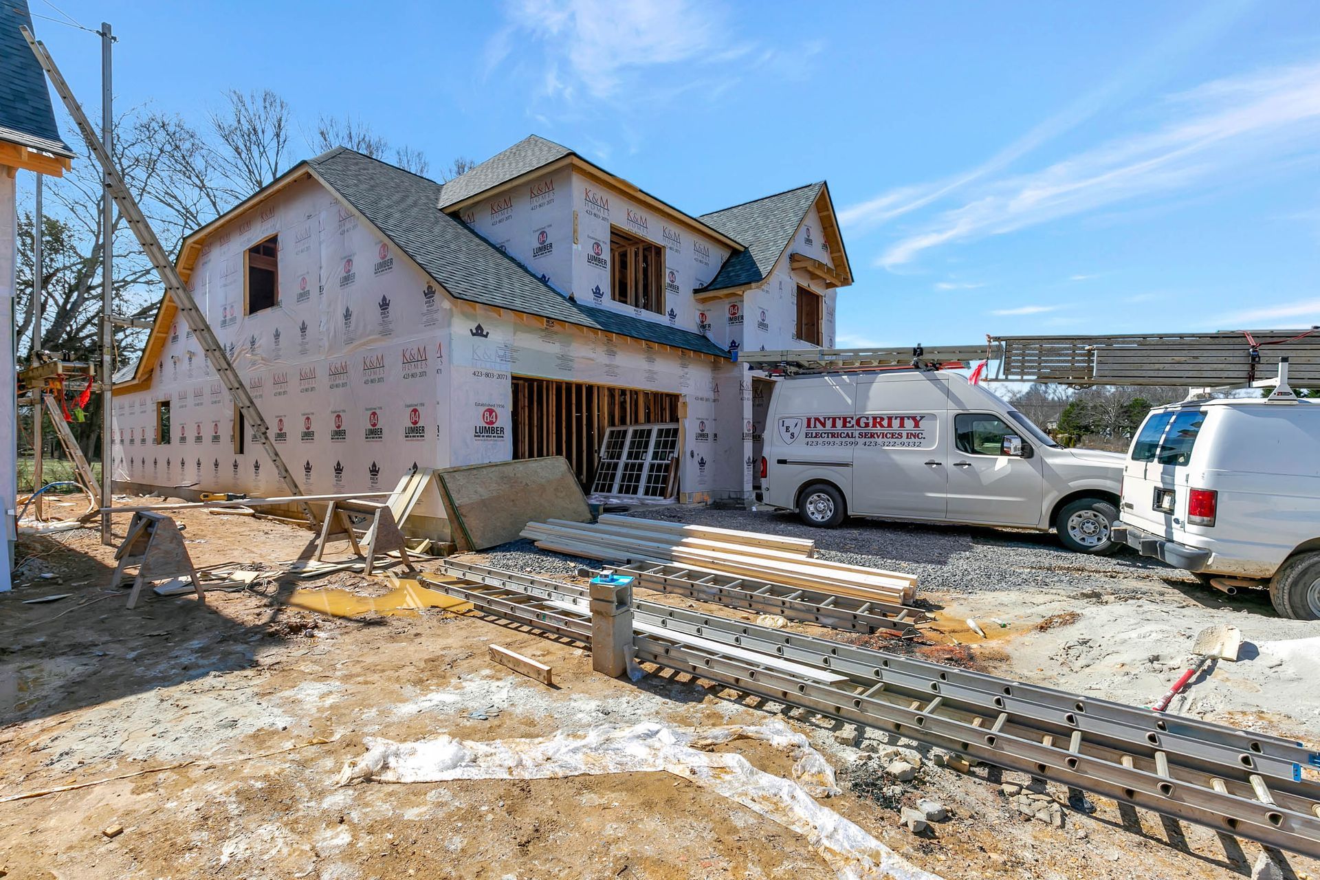 A white van is parked in front of a house under construction.