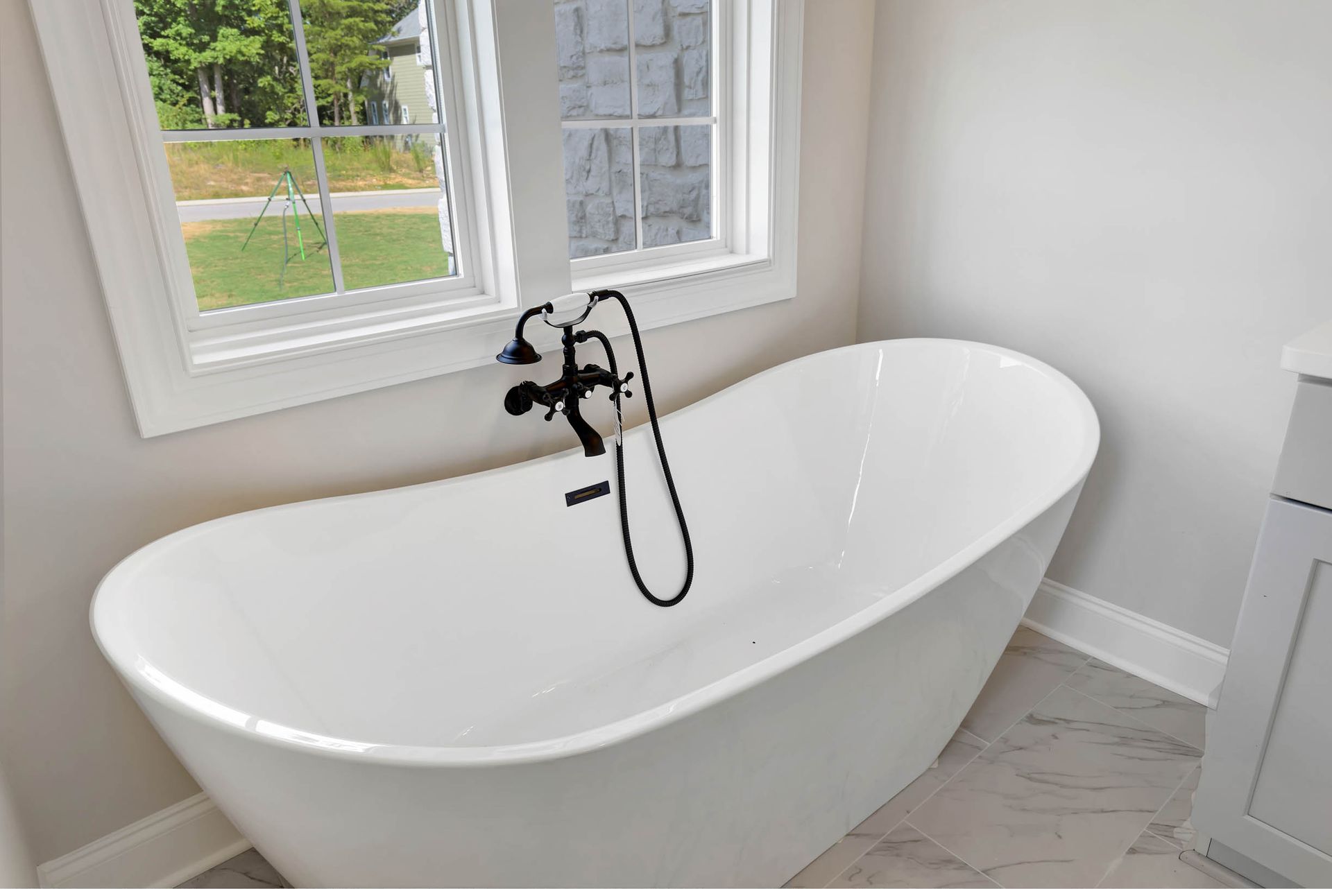 A white bathtub is sitting in a bathroom next to a window.