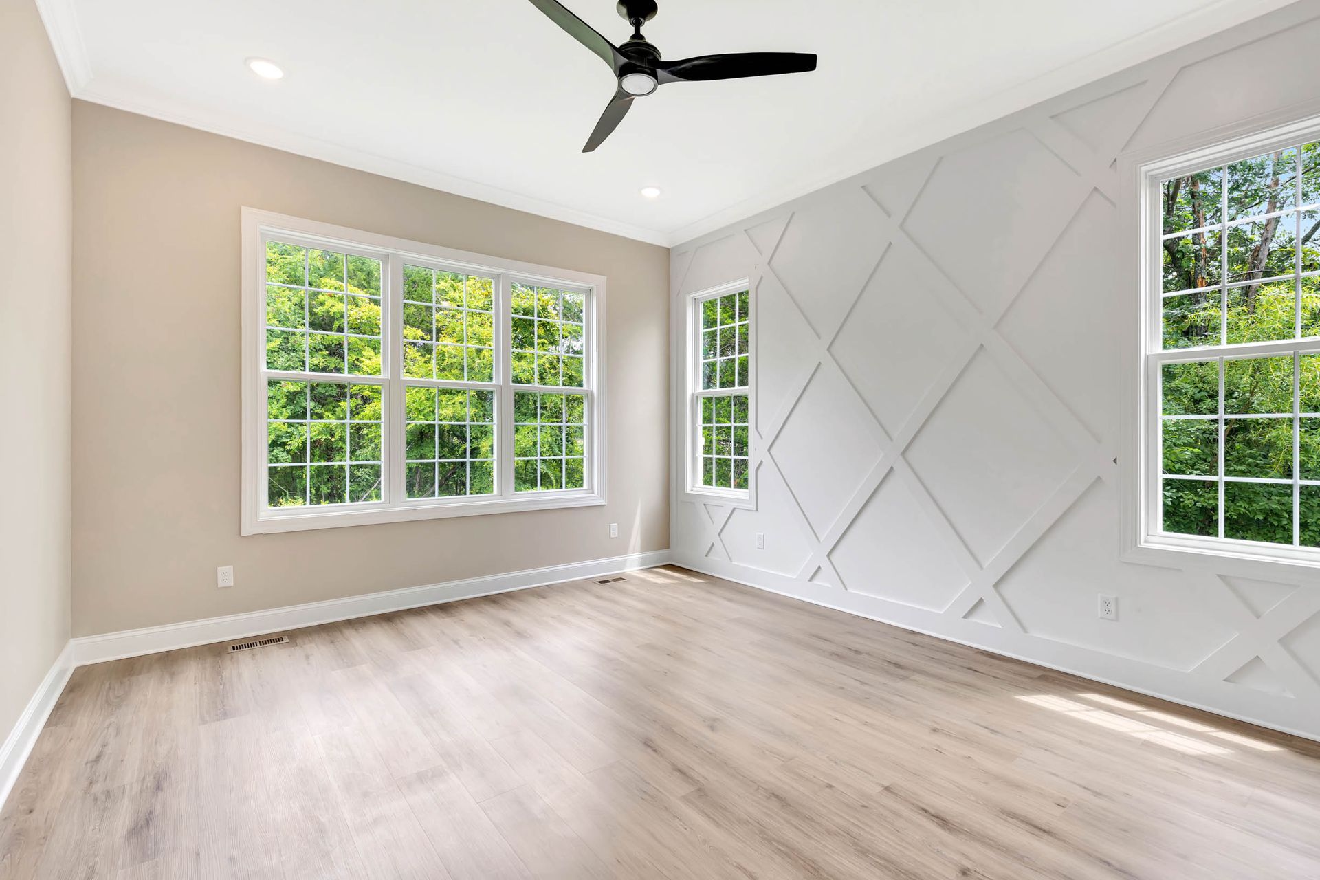 An empty room with a ceiling fan and lots of windows.