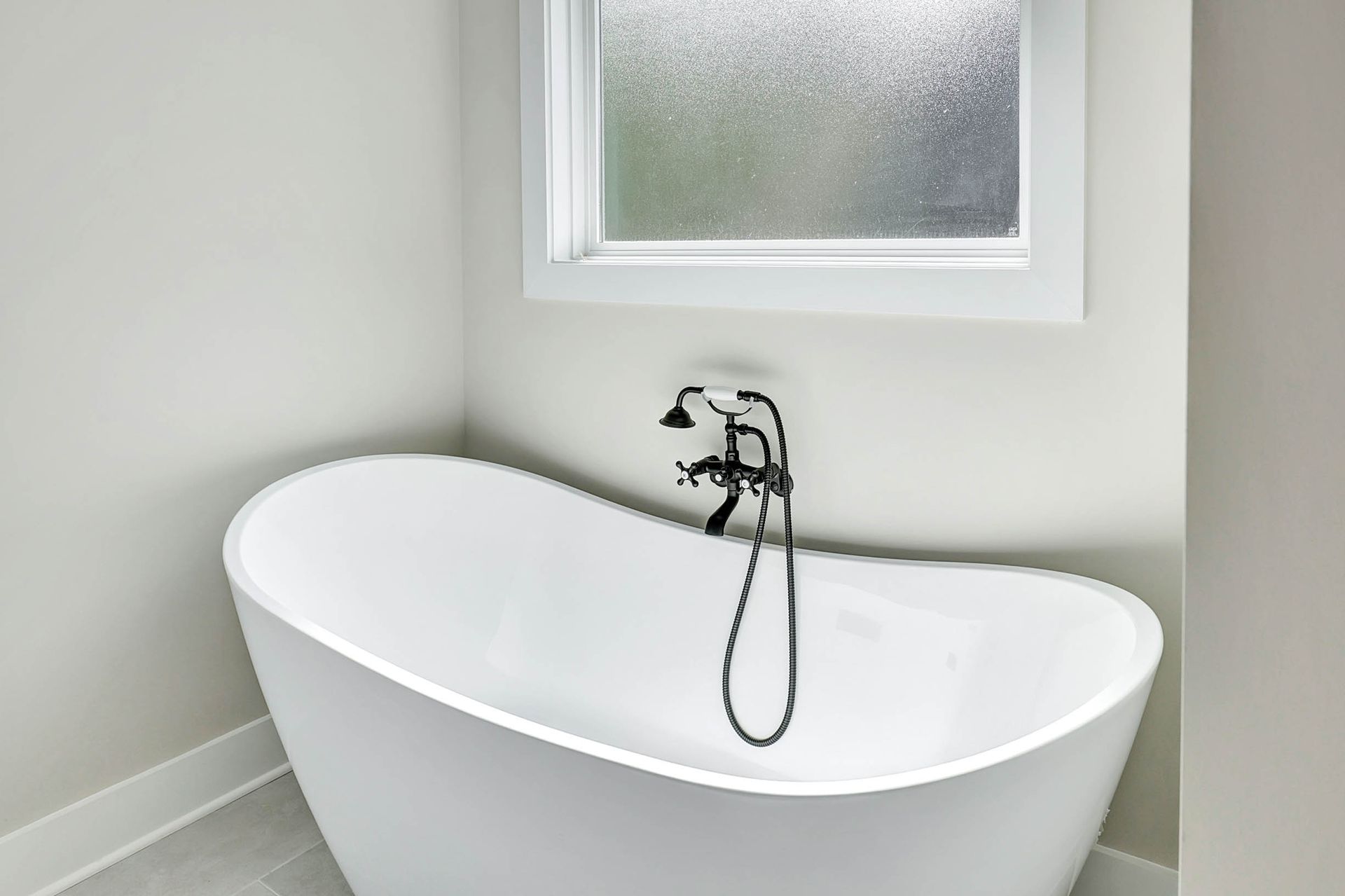 A white bathtub is sitting in a bathroom next to a window.