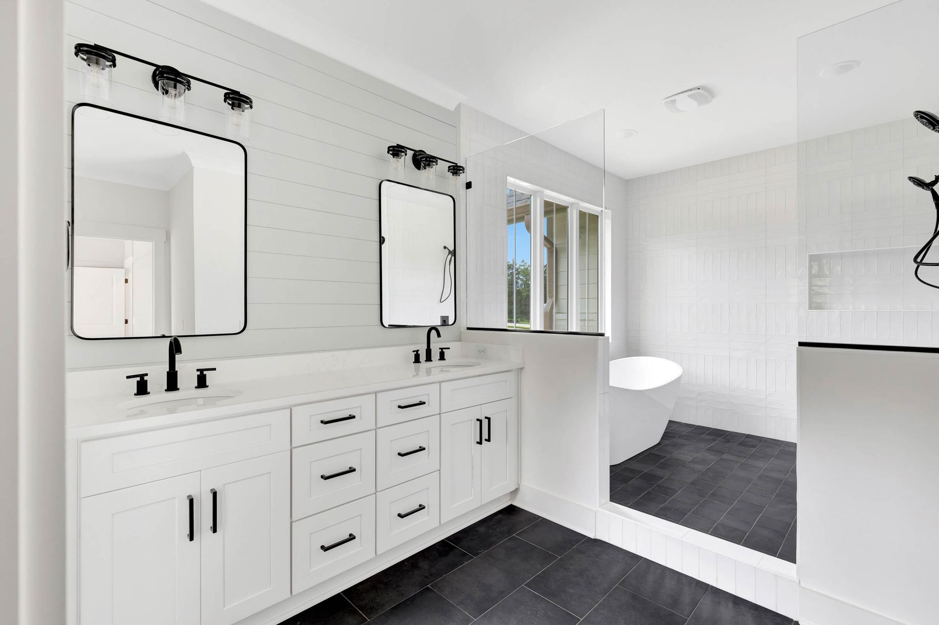 A bathroom with two sinks , two mirrors , a tub and a shower.