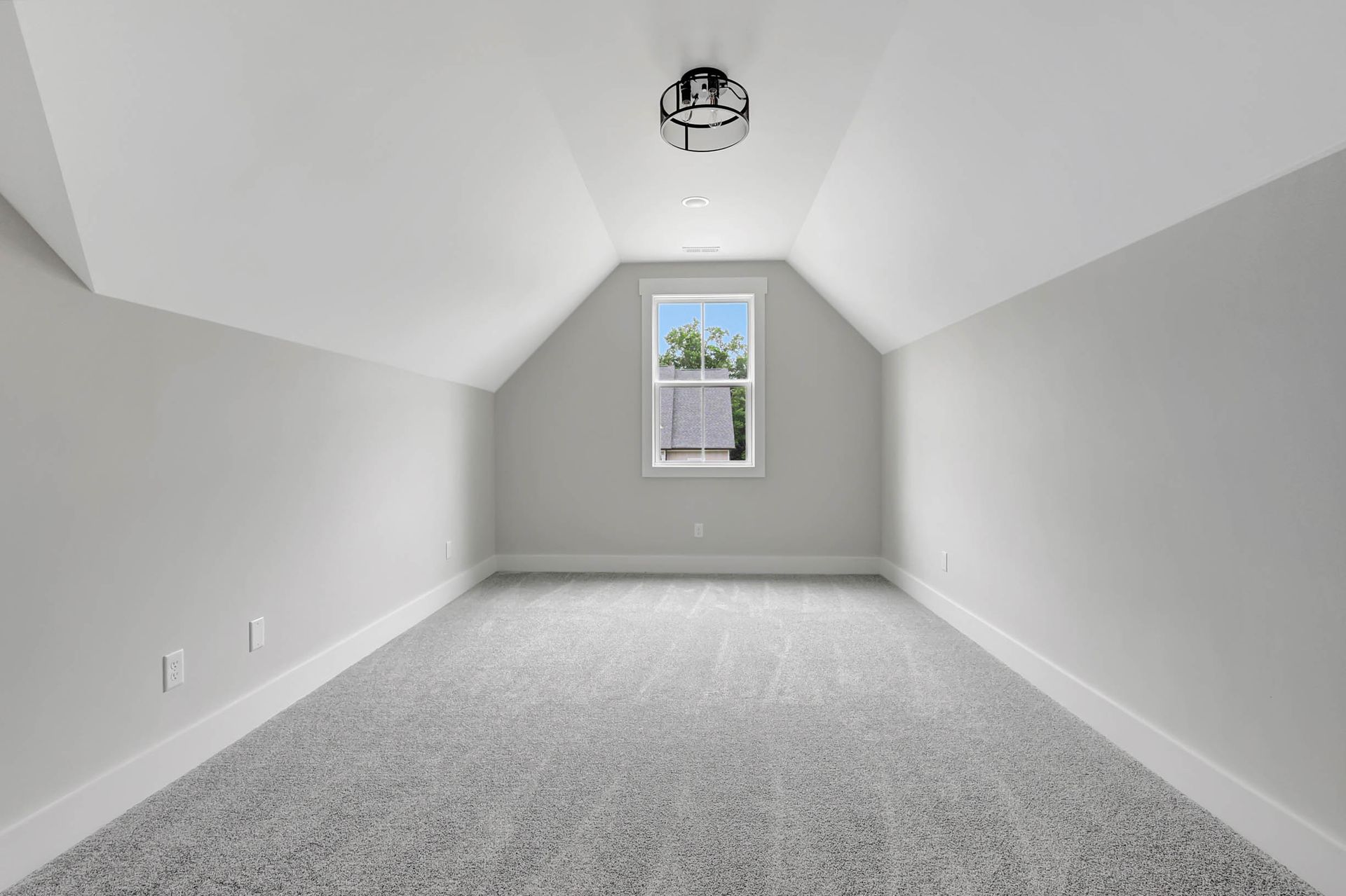 An empty attic with a window and a ceiling fan.