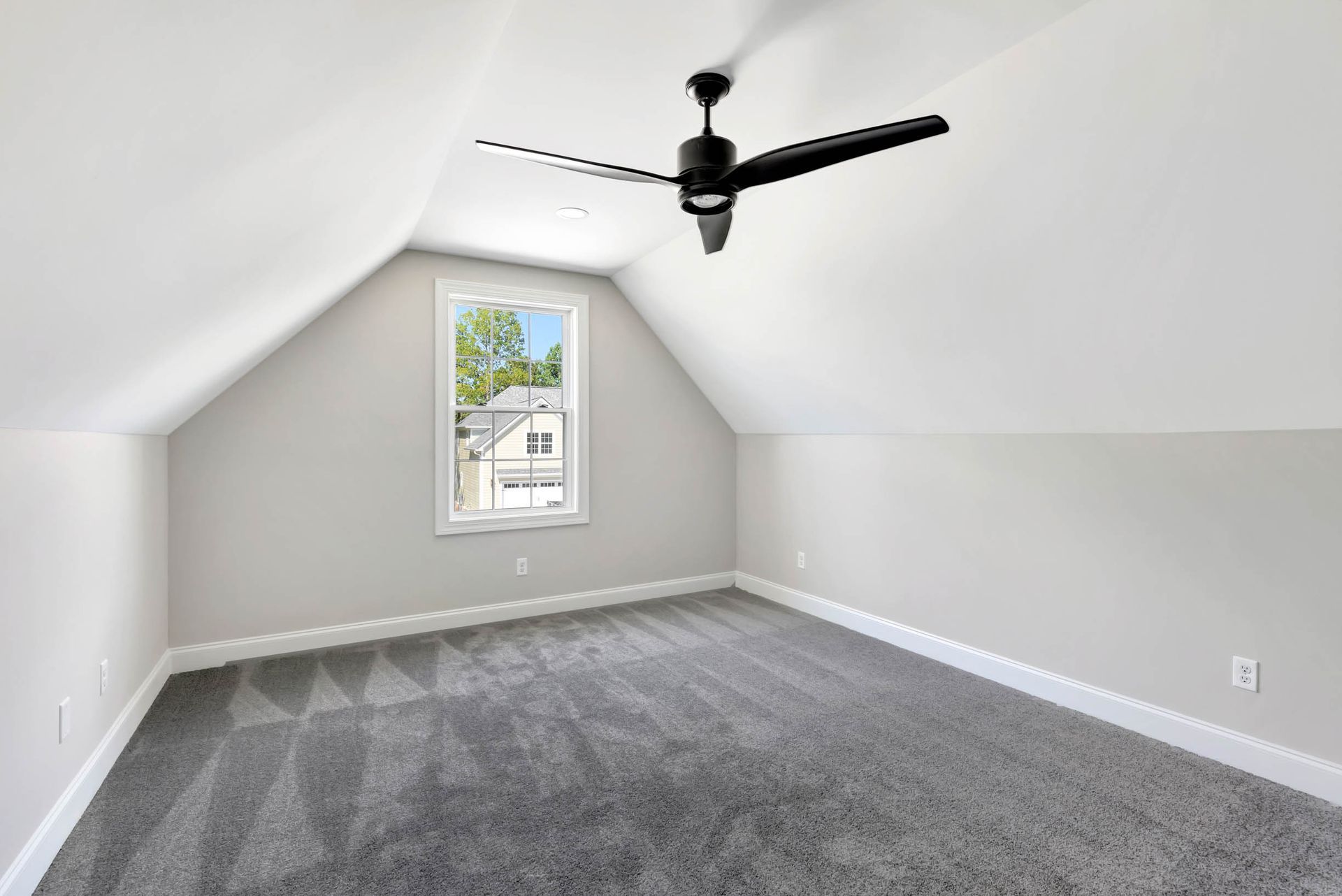 An empty bedroom with a ceiling fan and a window.