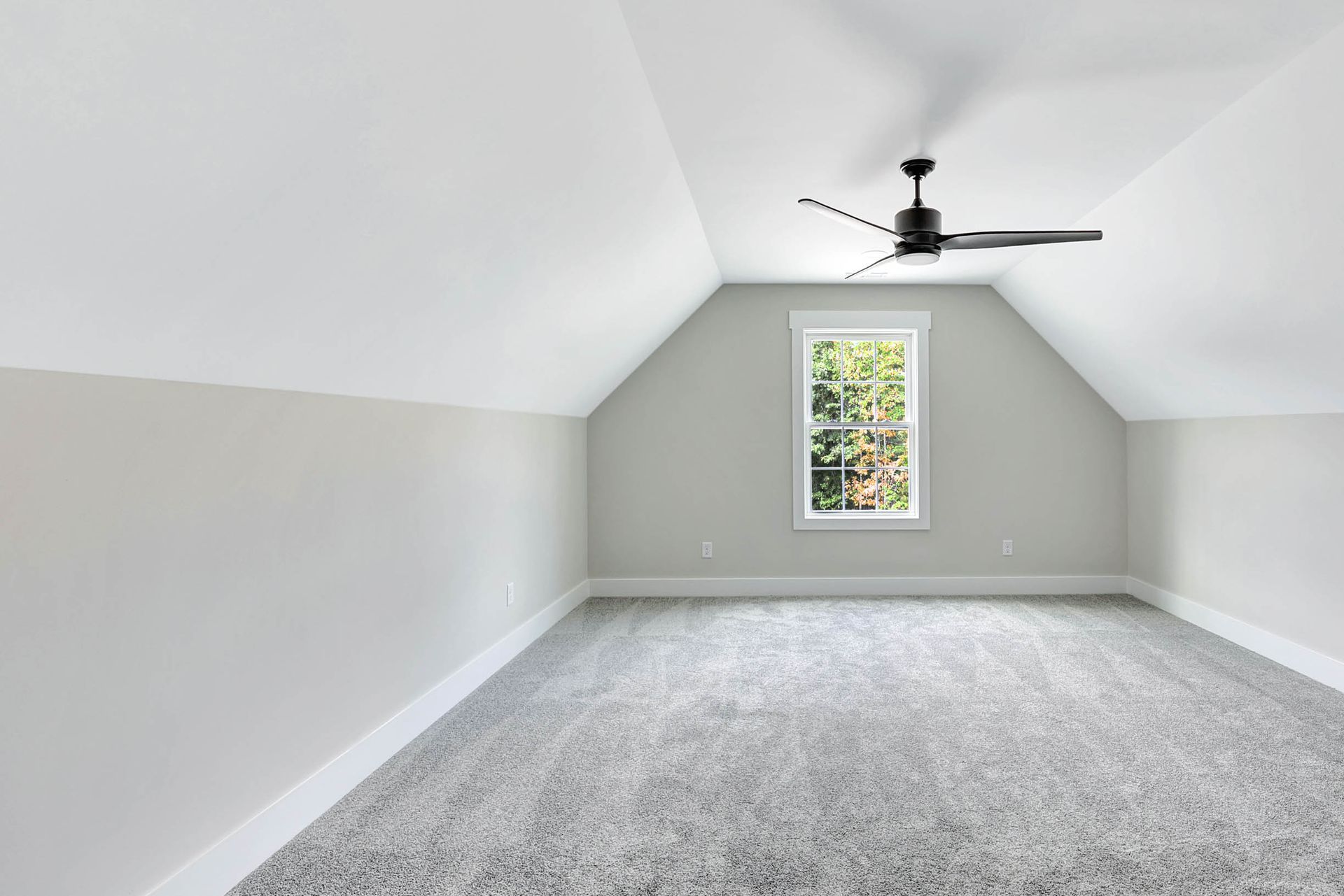 An empty room with a ceiling fan and a window.