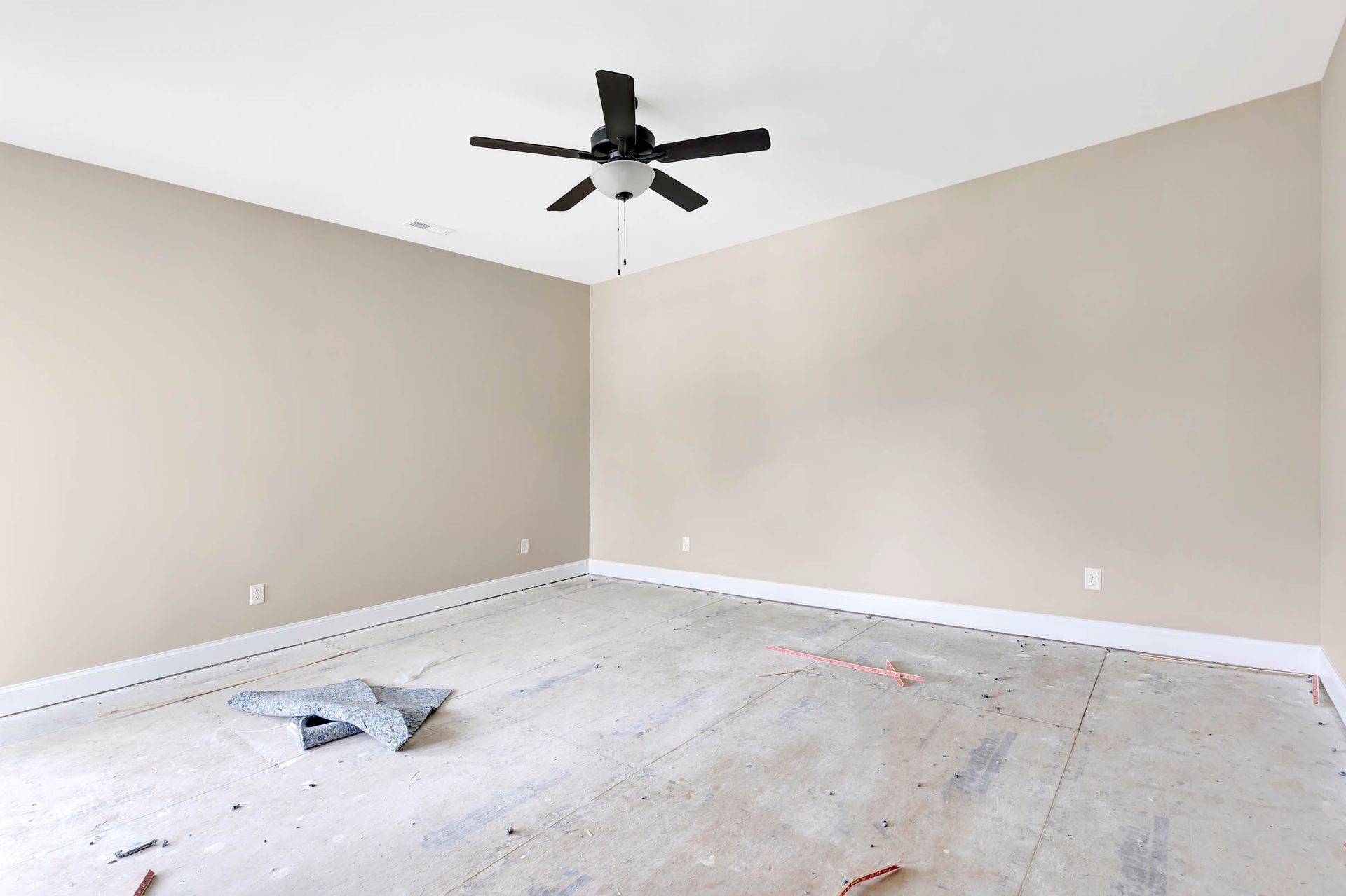 An empty room with a ceiling fan hanging from the ceiling.