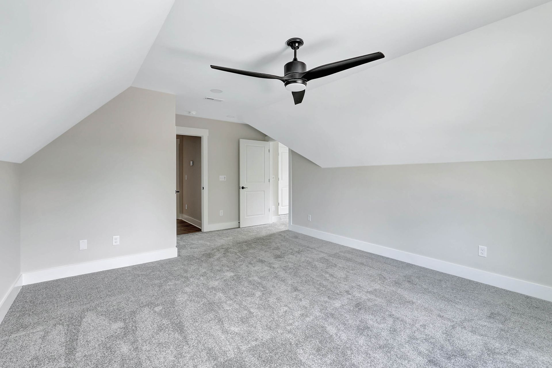 An empty bedroom with a ceiling fan and gray carpet.