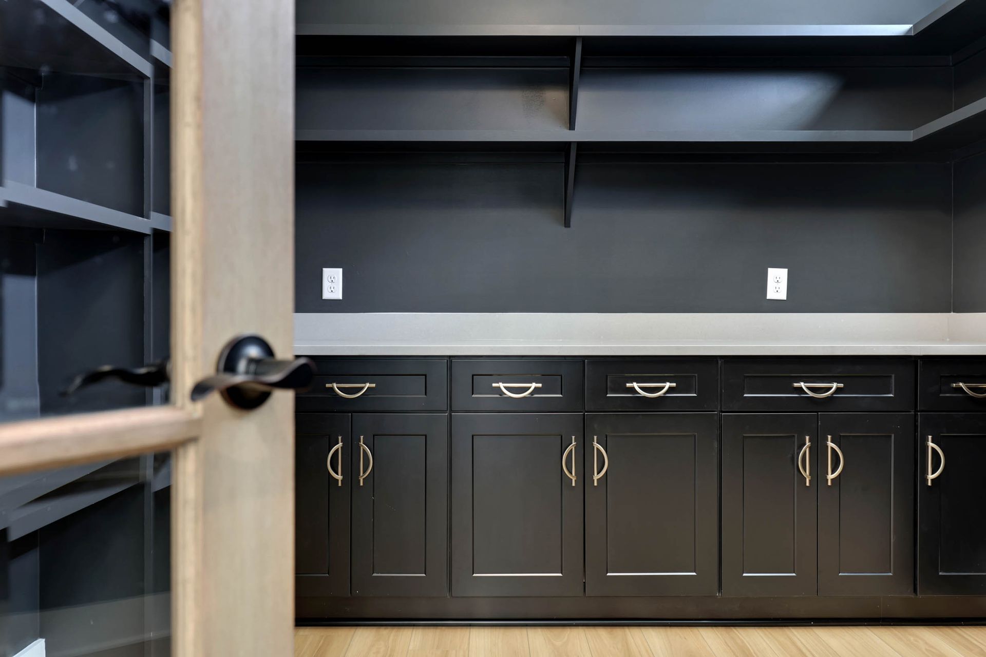 A kitchen with black cabinets , drawers , and shelves.