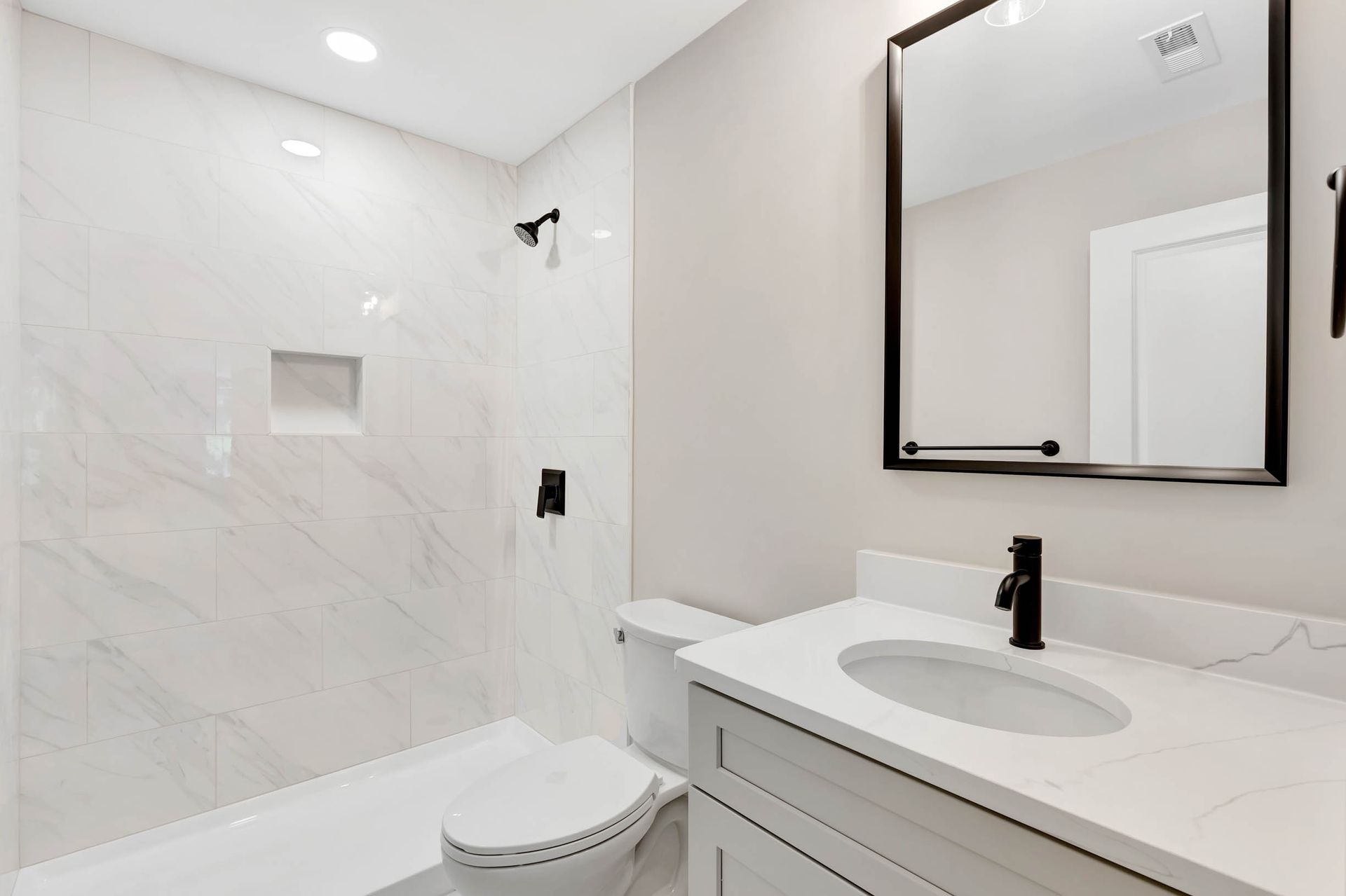 A bathroom with a toilet , sink , mirror and shower.