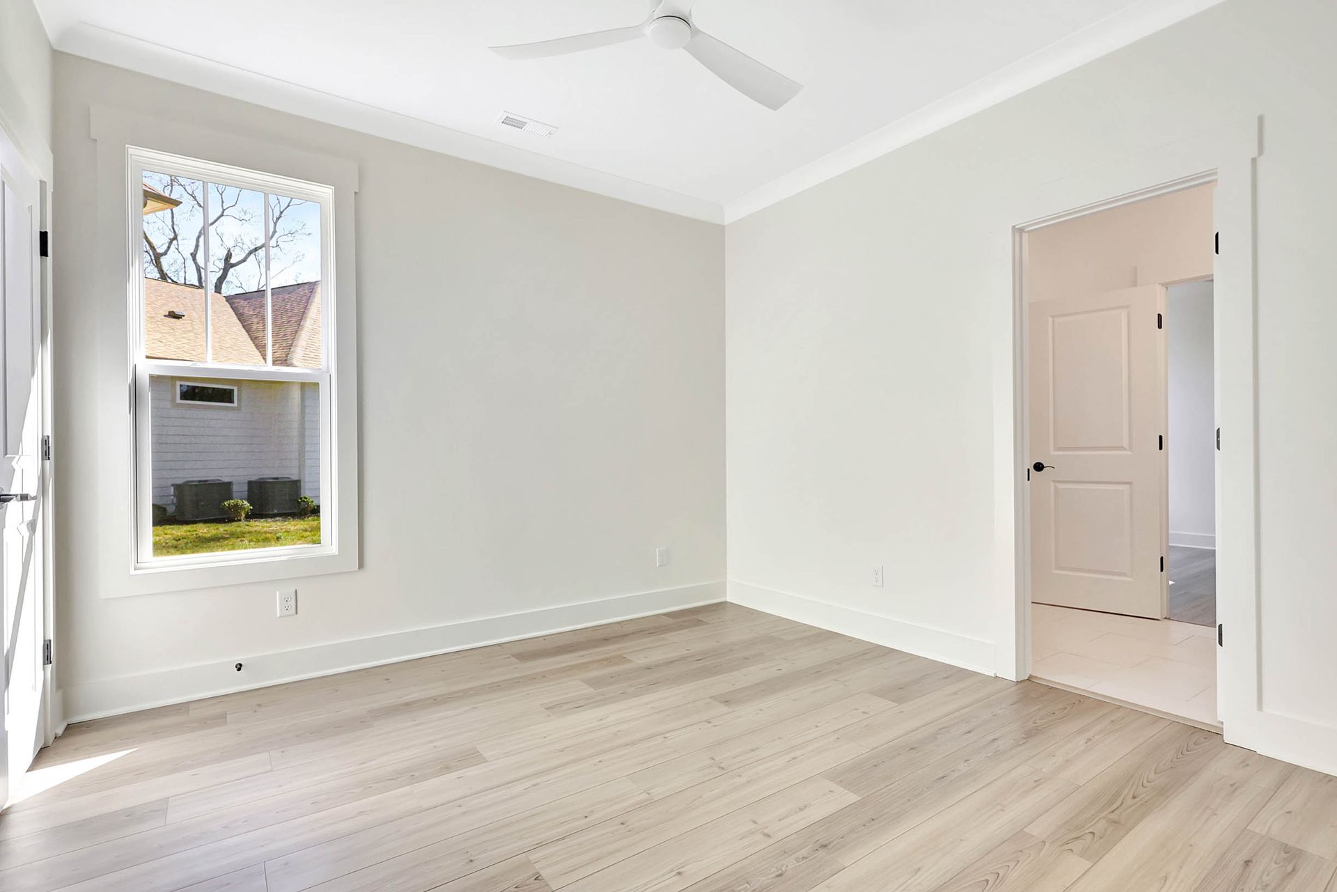 An empty room with a ceiling fan and a window.