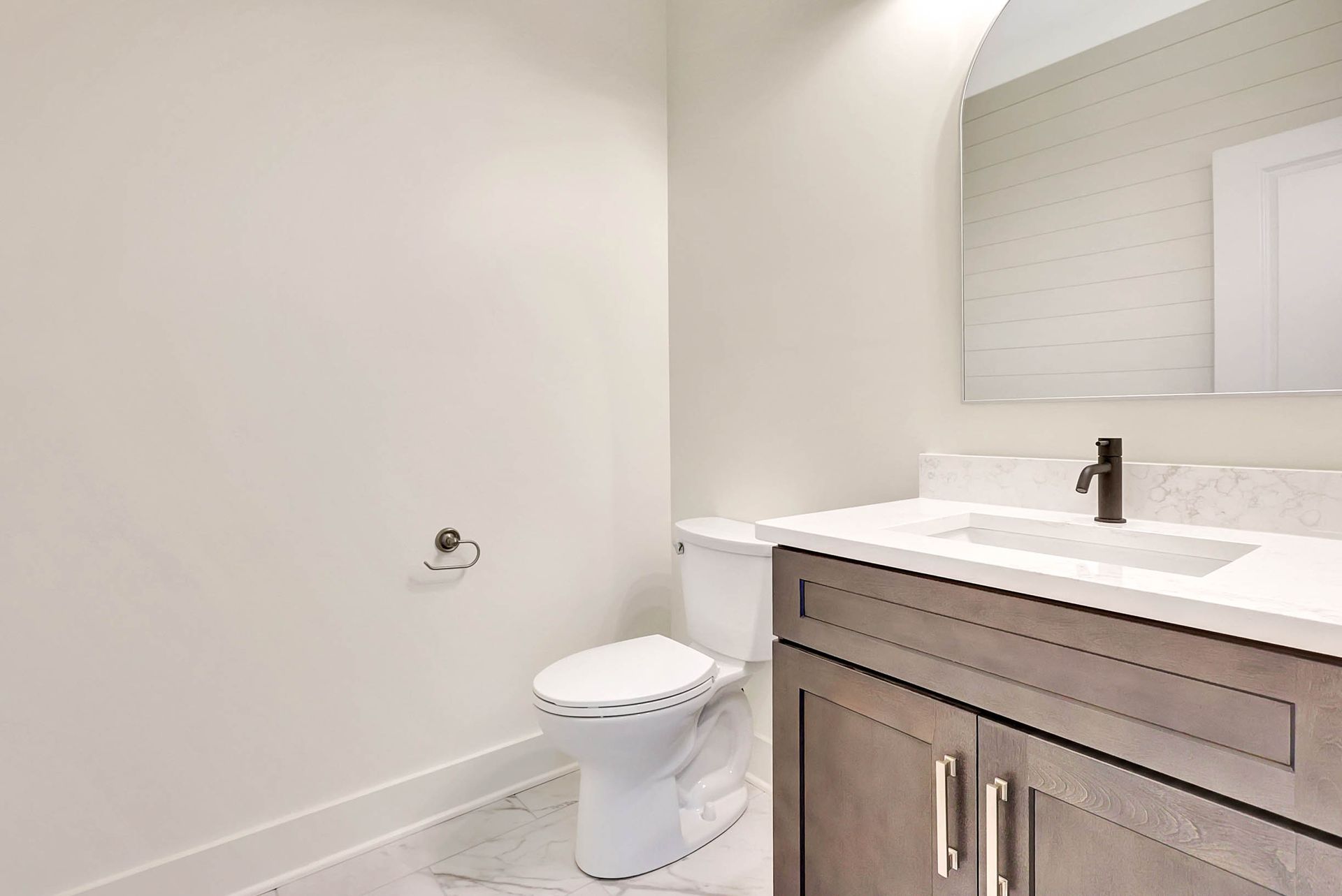 A bathroom with a toilet , sink and mirror.