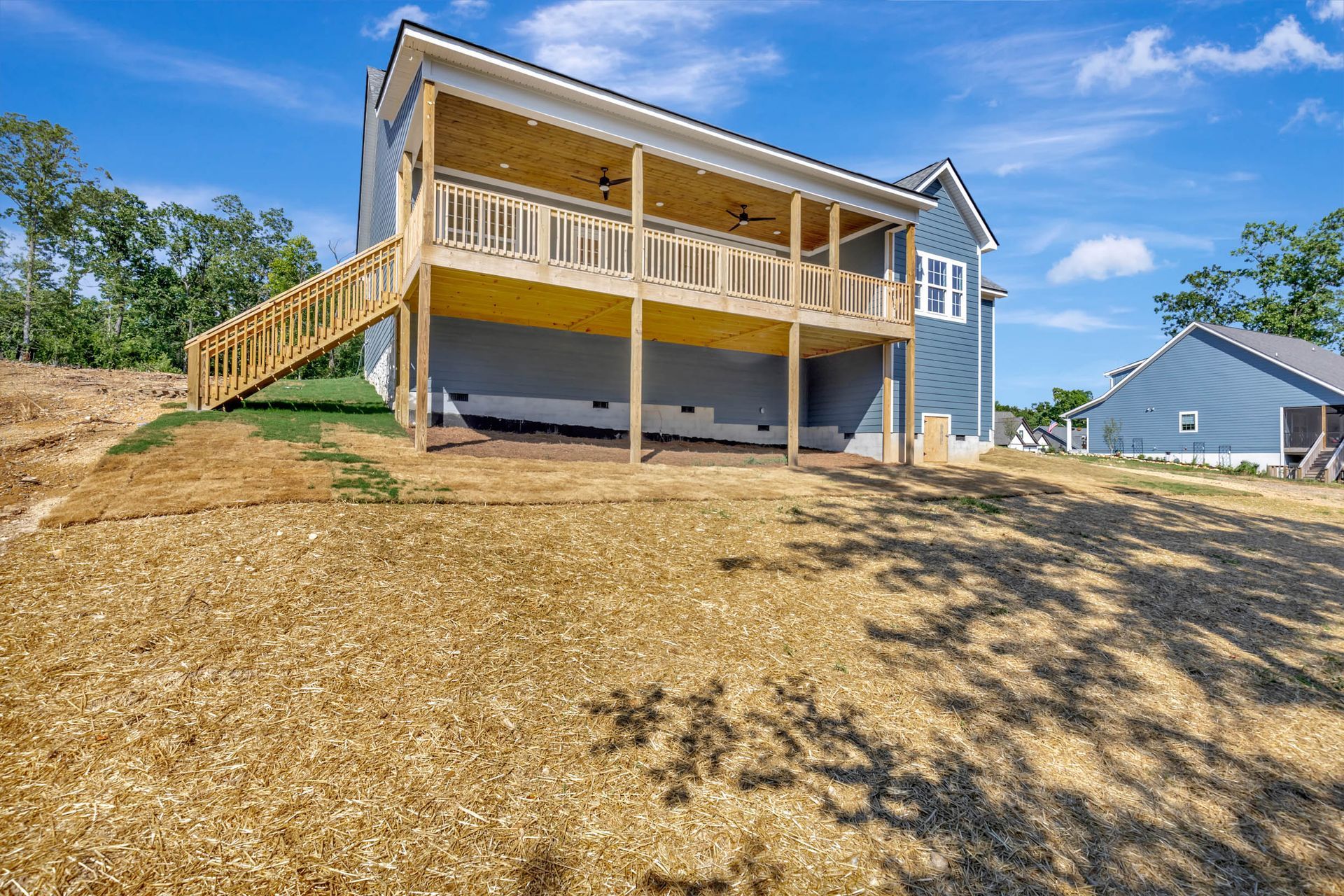The back of a house with a large deck and stairs leading up to it.