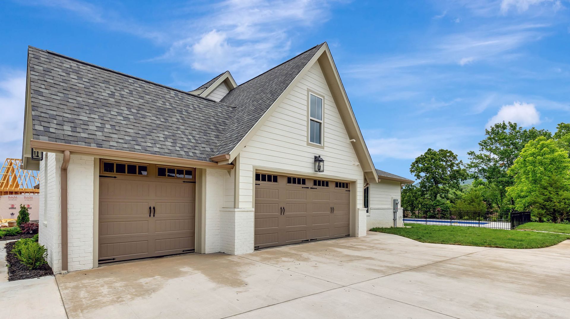 A white house with three garage doors and a gray roof.
