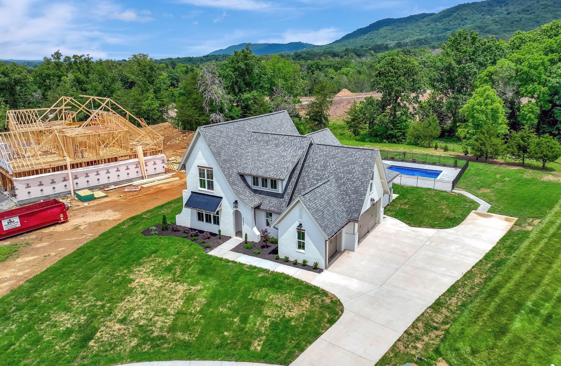 An aerial view of a house under construction in the middle of a lush green field.