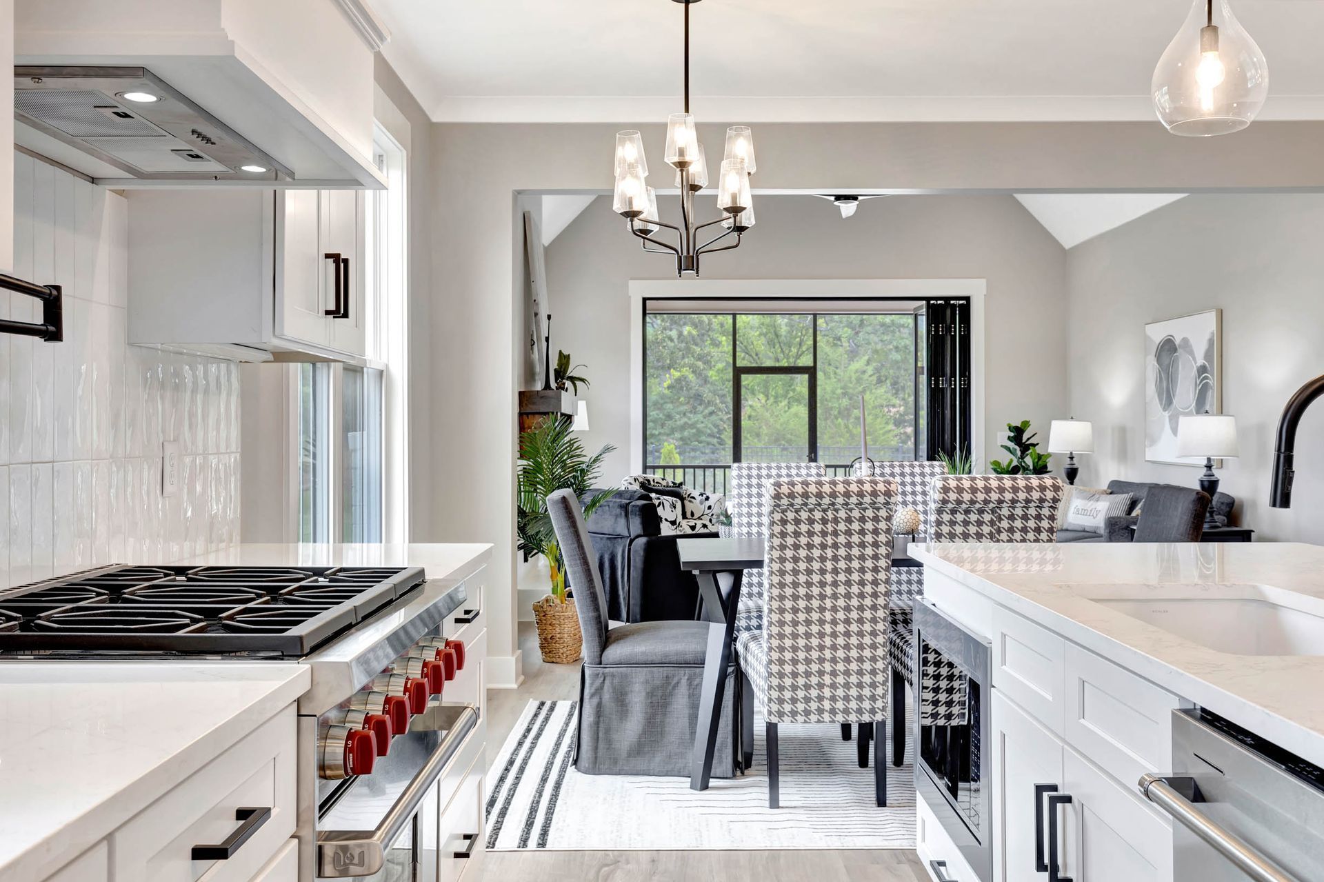 A kitchen with a stove and a sink and a dining room in the background.