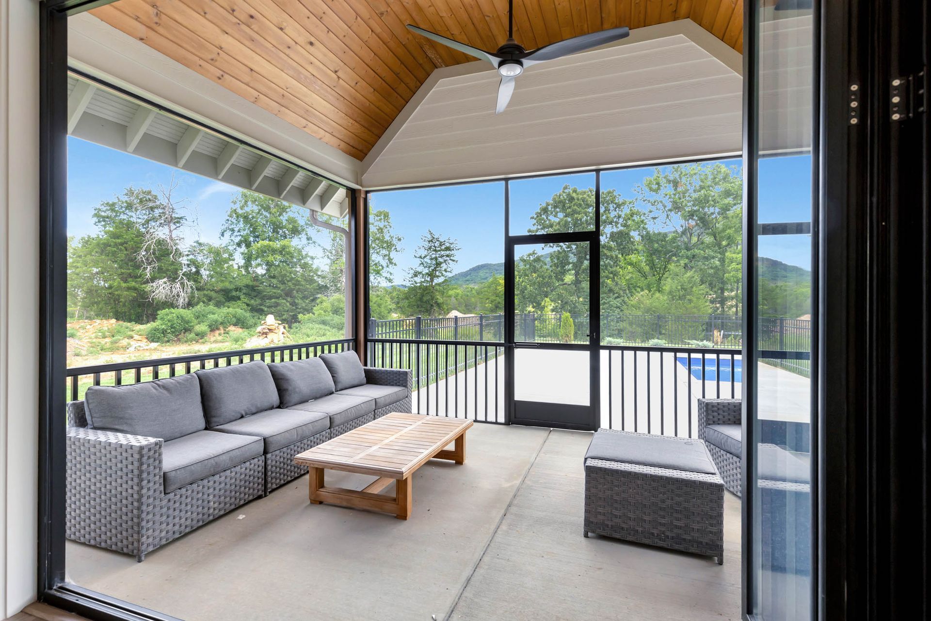 A screened in porch with furniture and a ceiling fan.