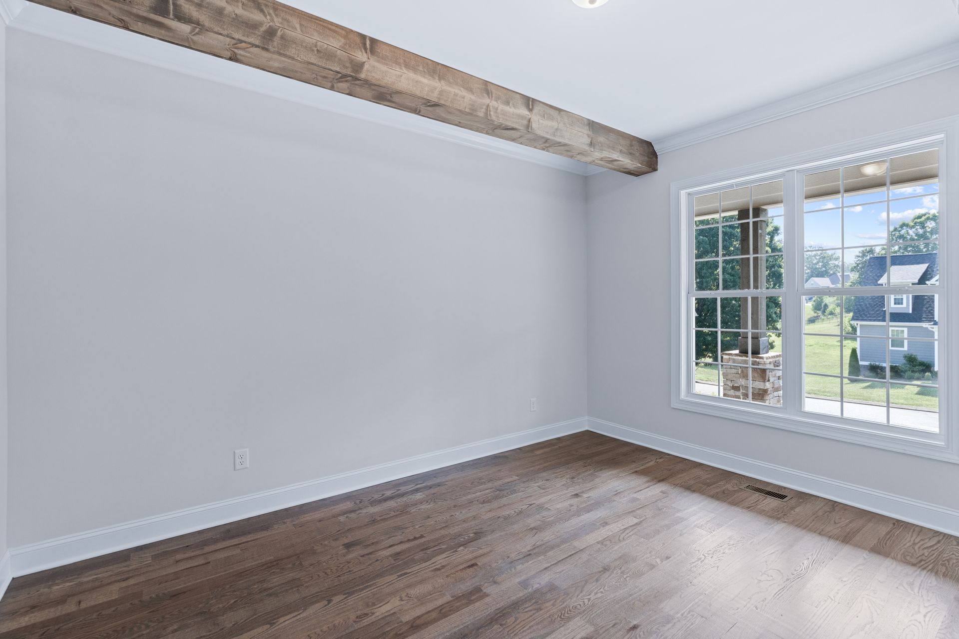 an empty room with hardwood floors and two windows .