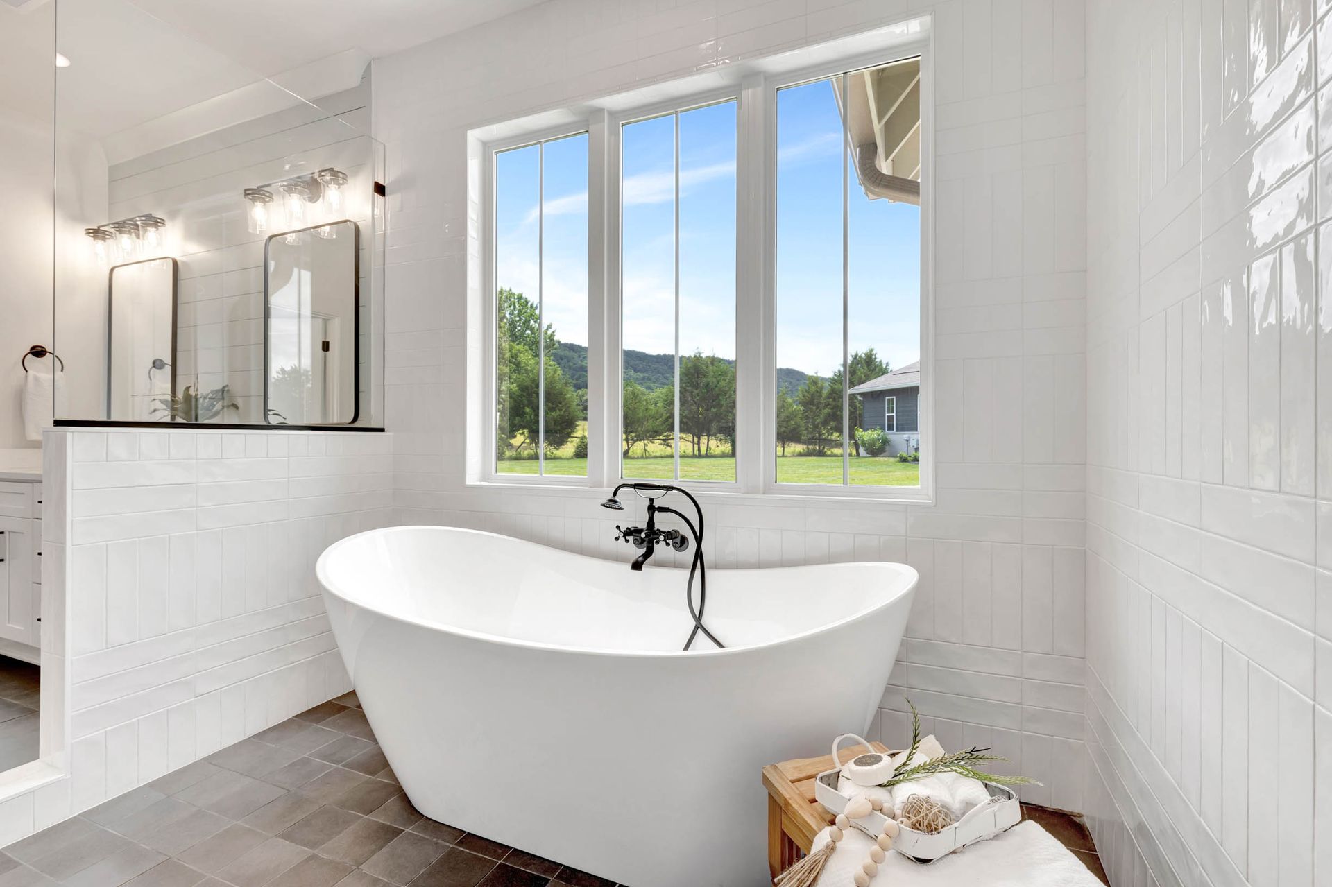 A bathroom with a tub , sink , mirror and window.