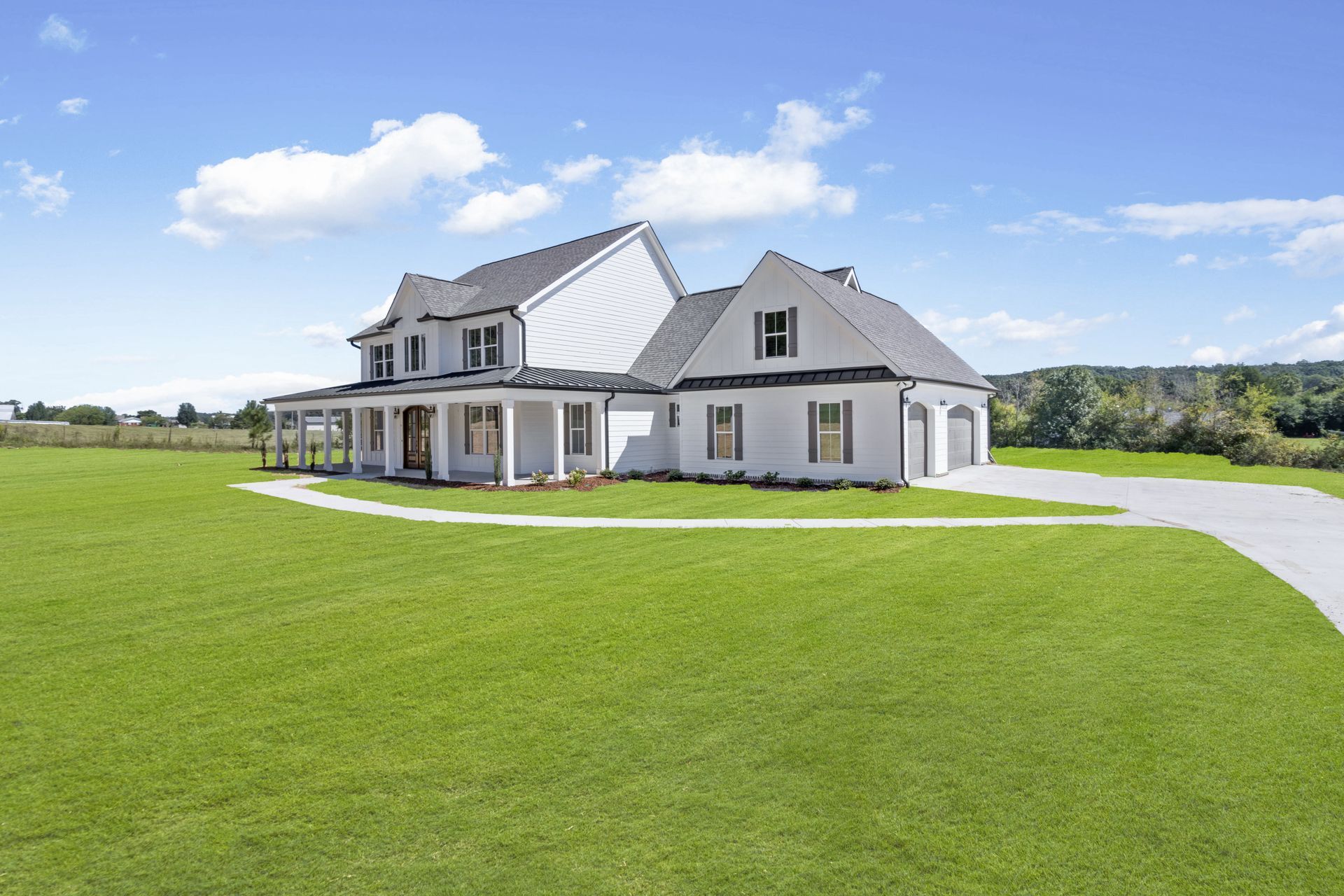 a large white house is sitting on top of a lush green field .