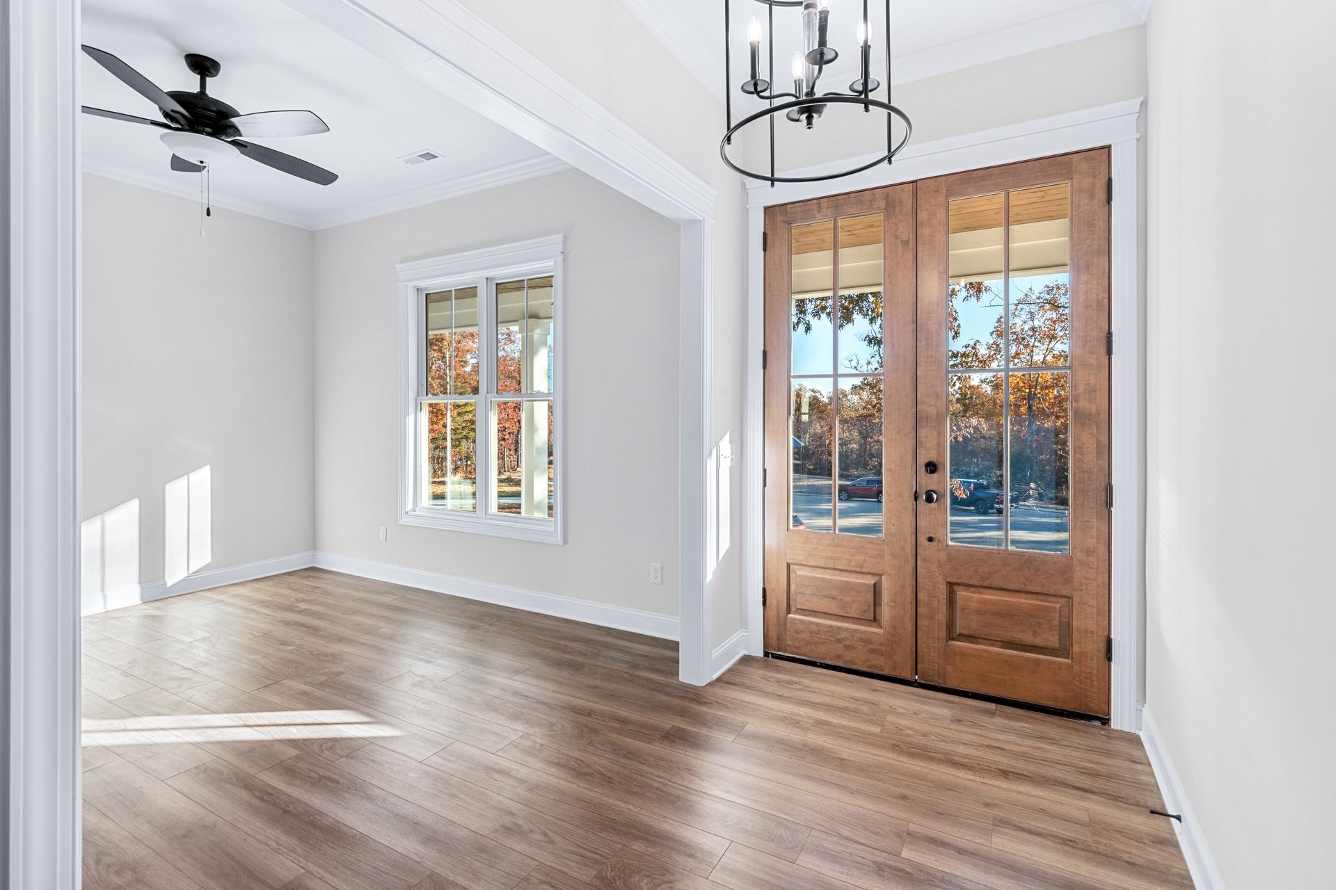 an empty living room with hardwood floors and a ceiling fan .