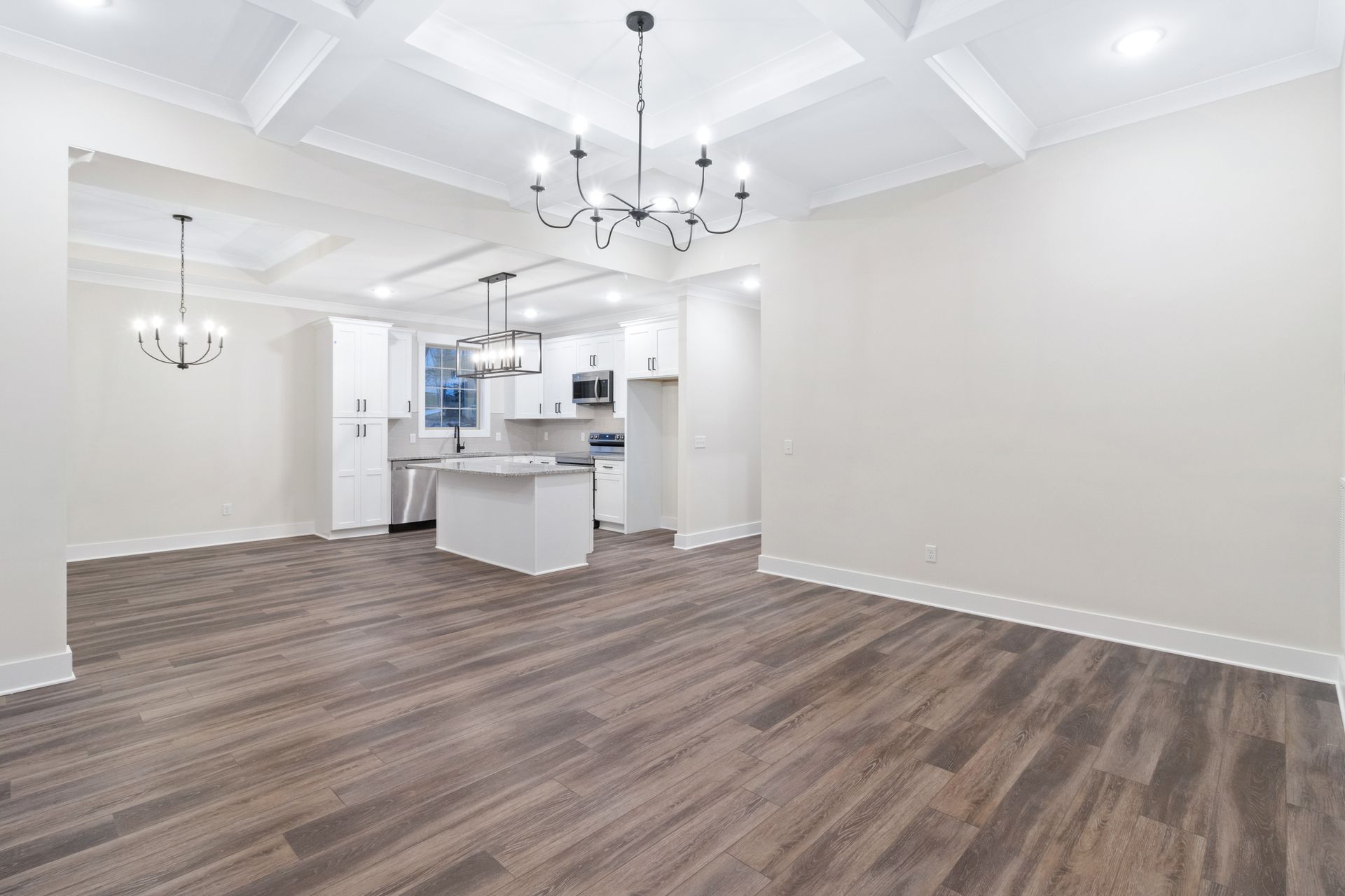 a living room with hardwood floors and a kitchen in the background .