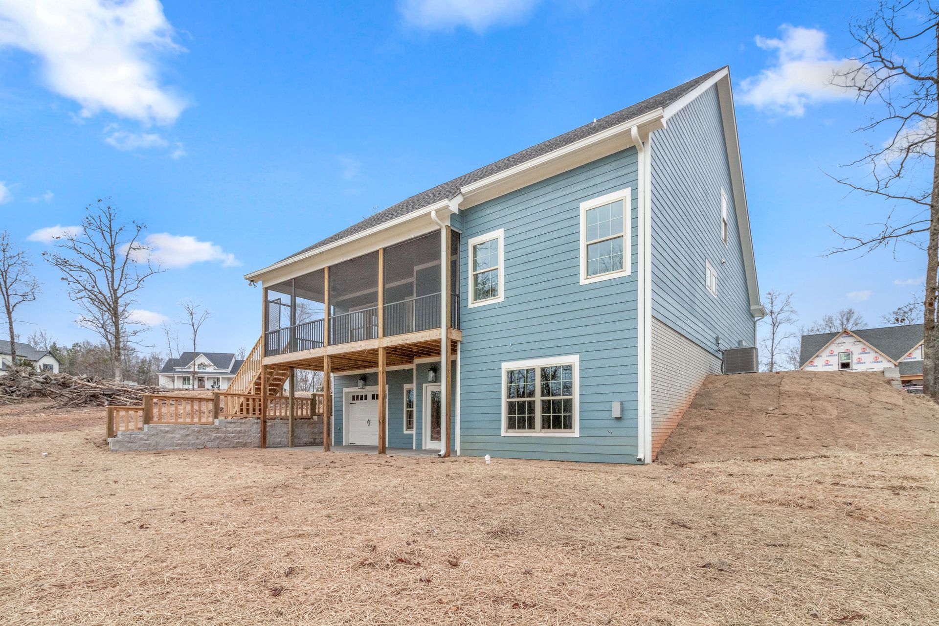 the back of a house with a screened in porch and a large deck .