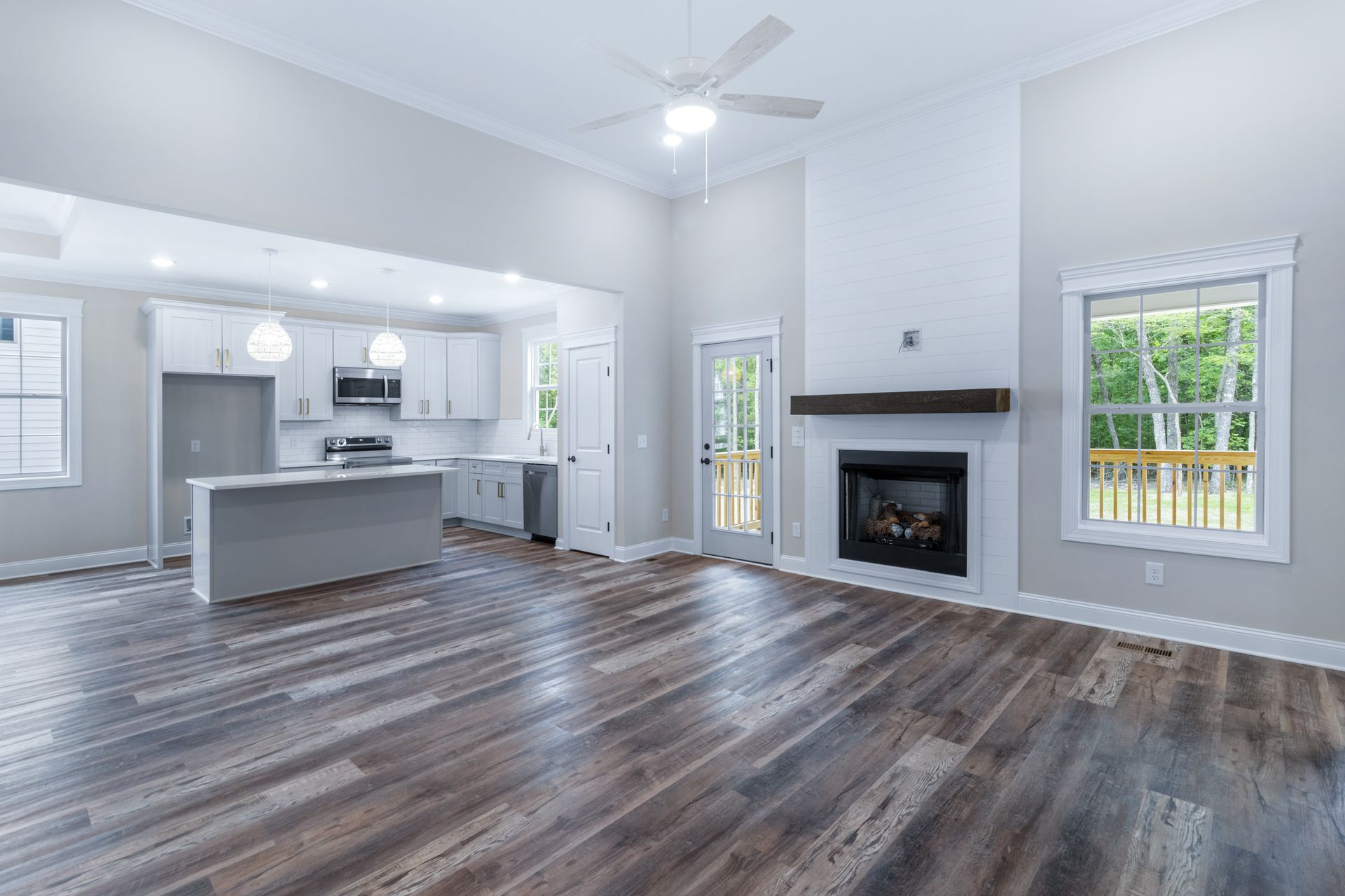 a living room with hardwood floors , a fireplace , and a kitchen .