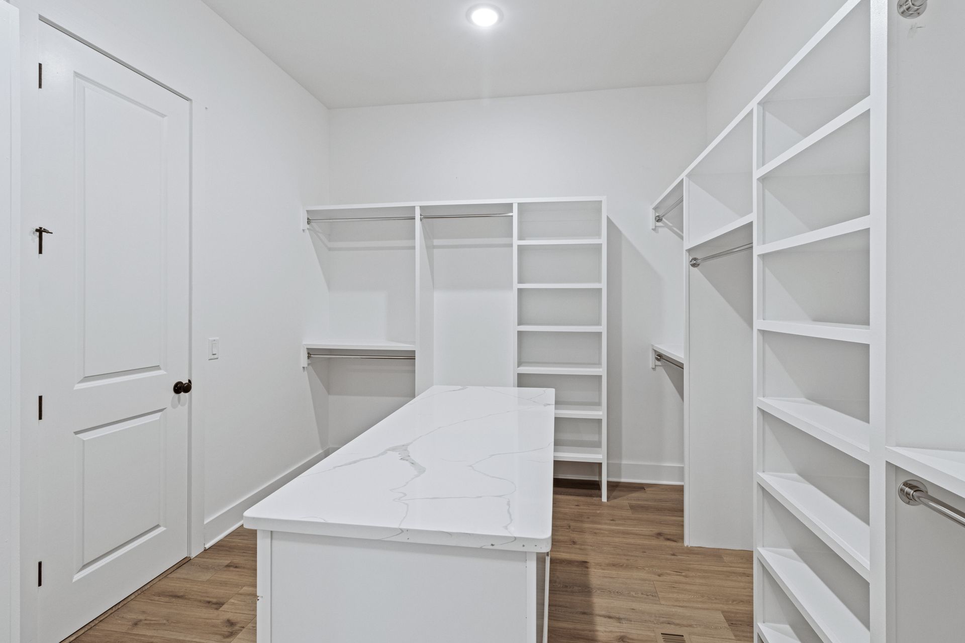 a walk in closet with lots of shelves and a table .