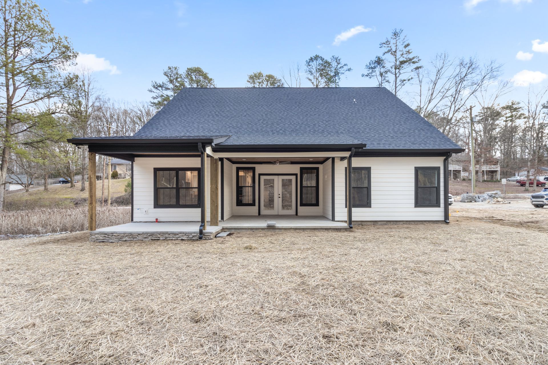 a white house with a black roof is sitting on top of a dirt field .
