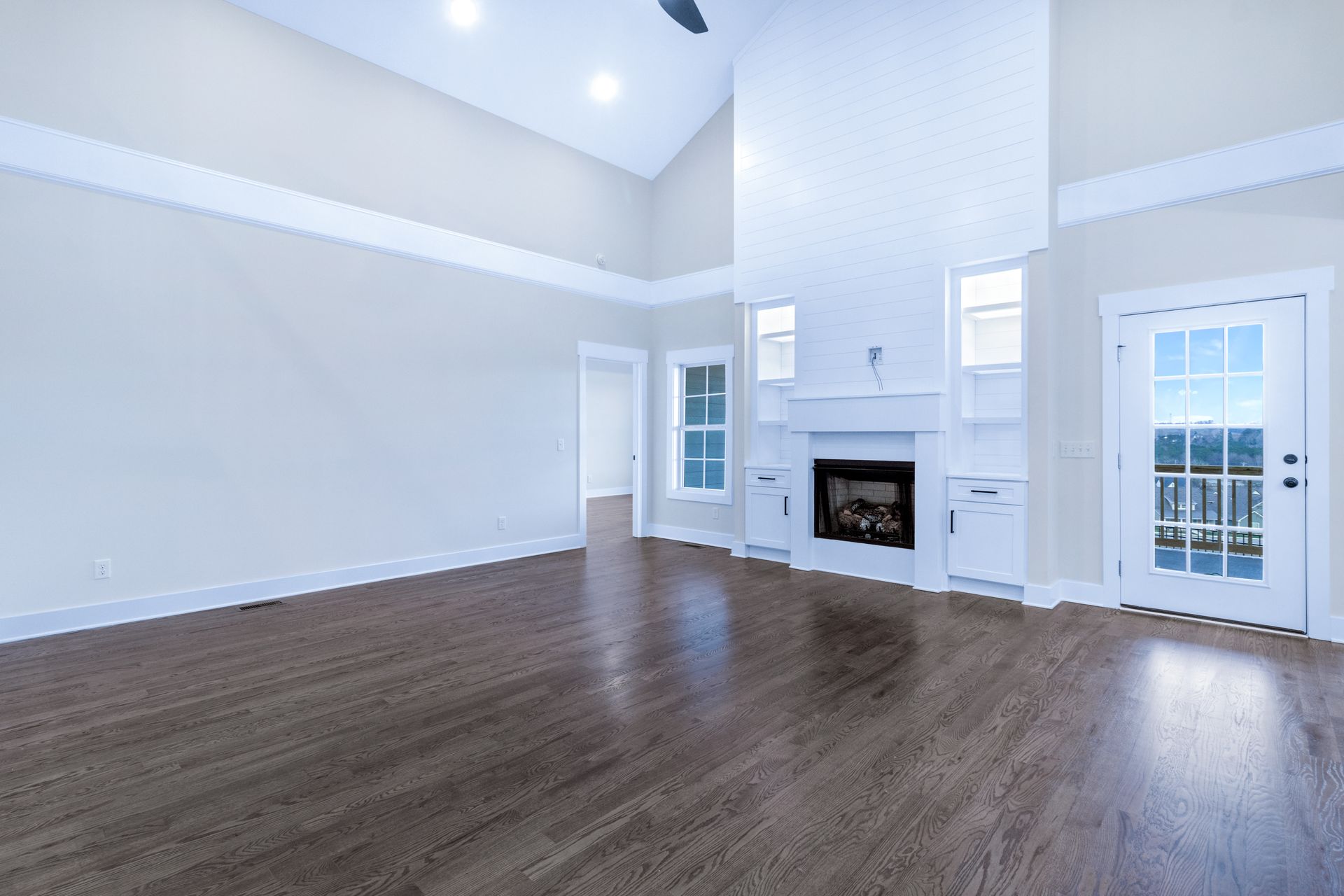 an empty living room with hardwood floors and a fireplace .