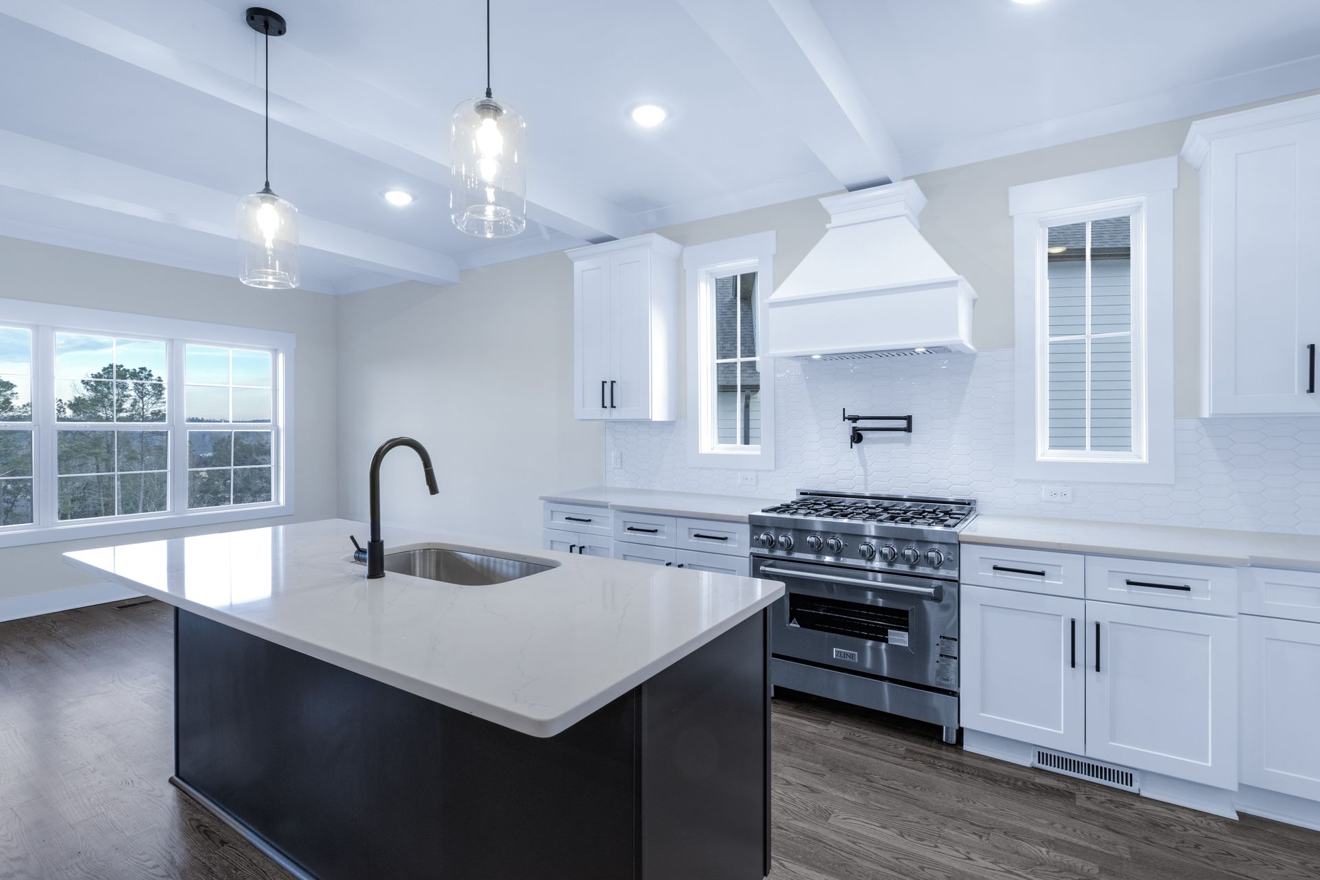 a kitchen with white cabinets , a stove , a sink , and a large island .