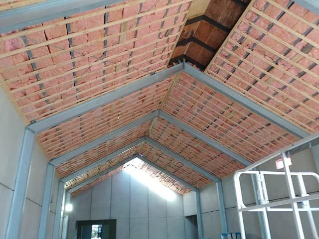 Interior of a metal shed with exposed roof trusses, brick panels, and skylight openings.