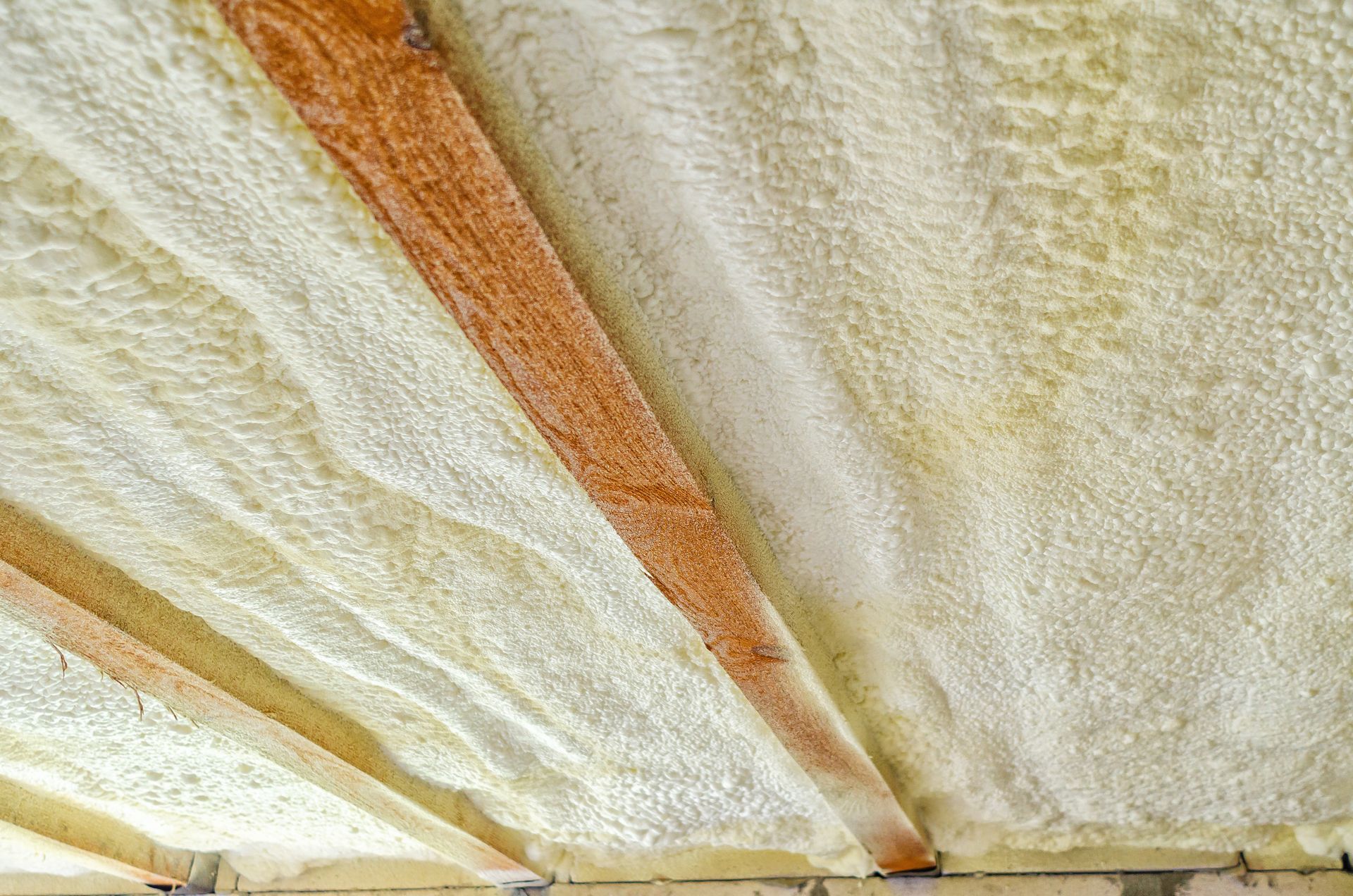 Ceiling featuring exposed wood beams and insulation material.